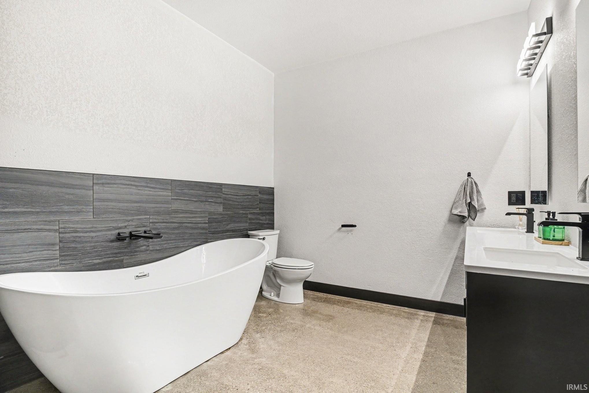 Freestanding soaking tub with dark wall-mounted fixtures