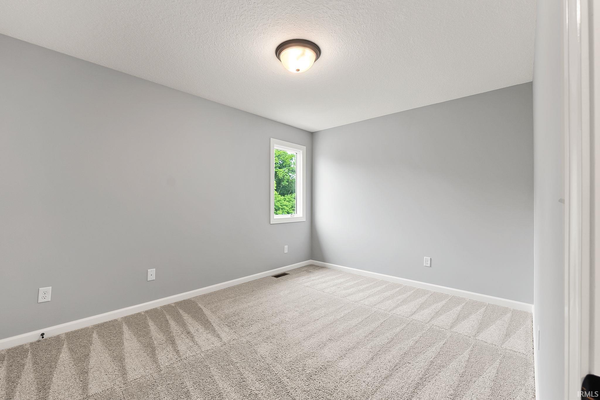 Neutral-toned room with light gray walls and a textured carpet featuring a geometric pattern