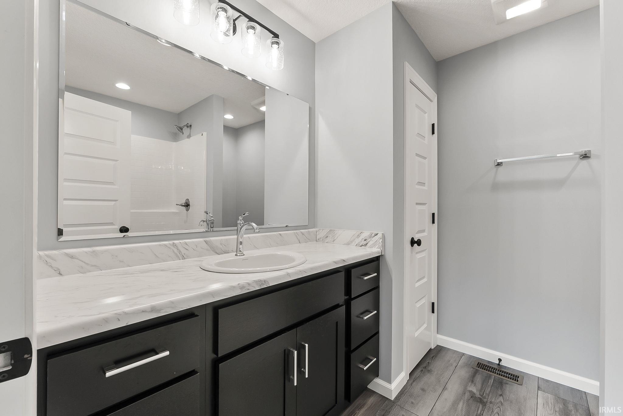 Bathroom featuring a dark wood-finish vanity with a white marble-patterned countertop and an undermount sink