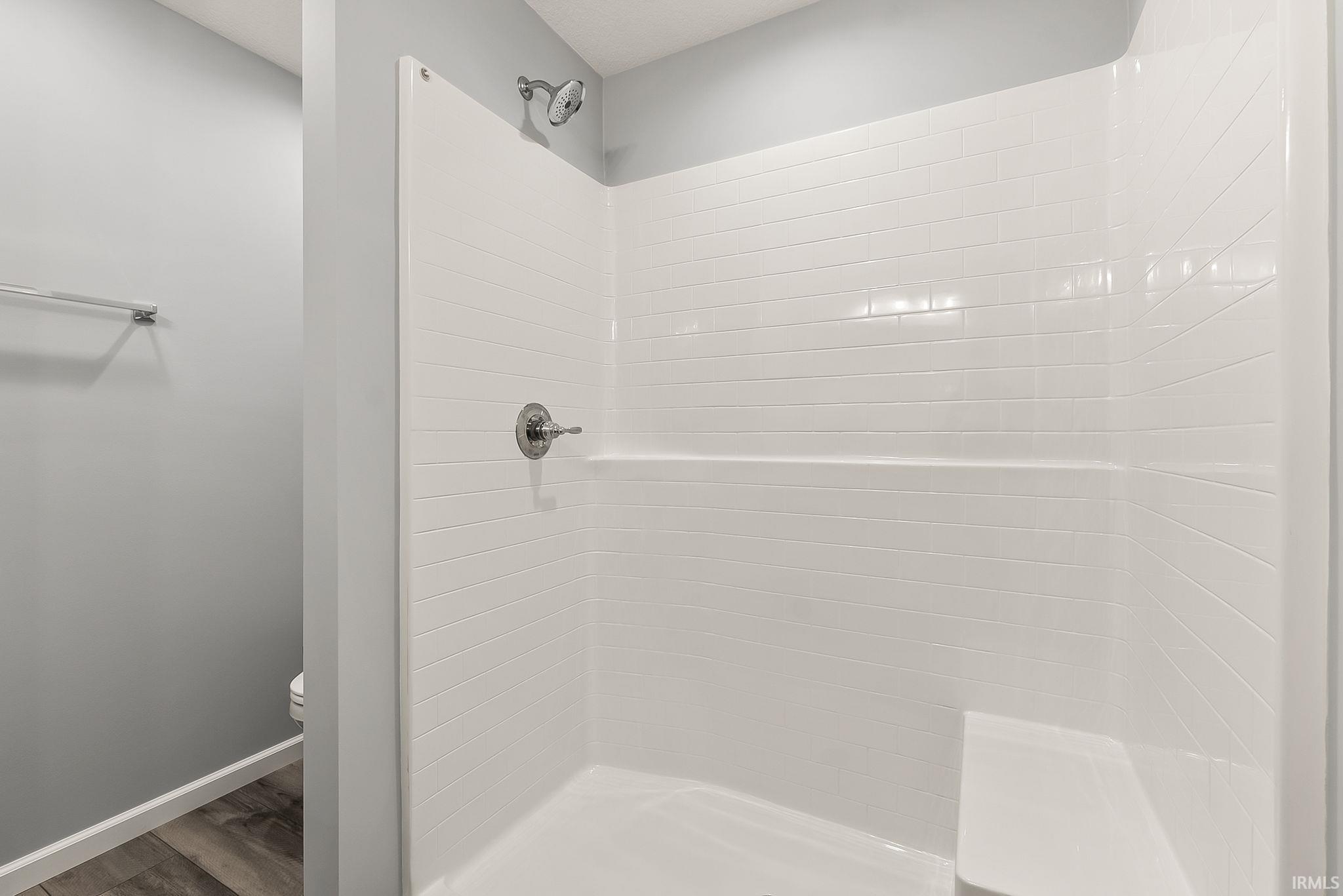 White subway tile pattern shower surround with an integrated shower bench