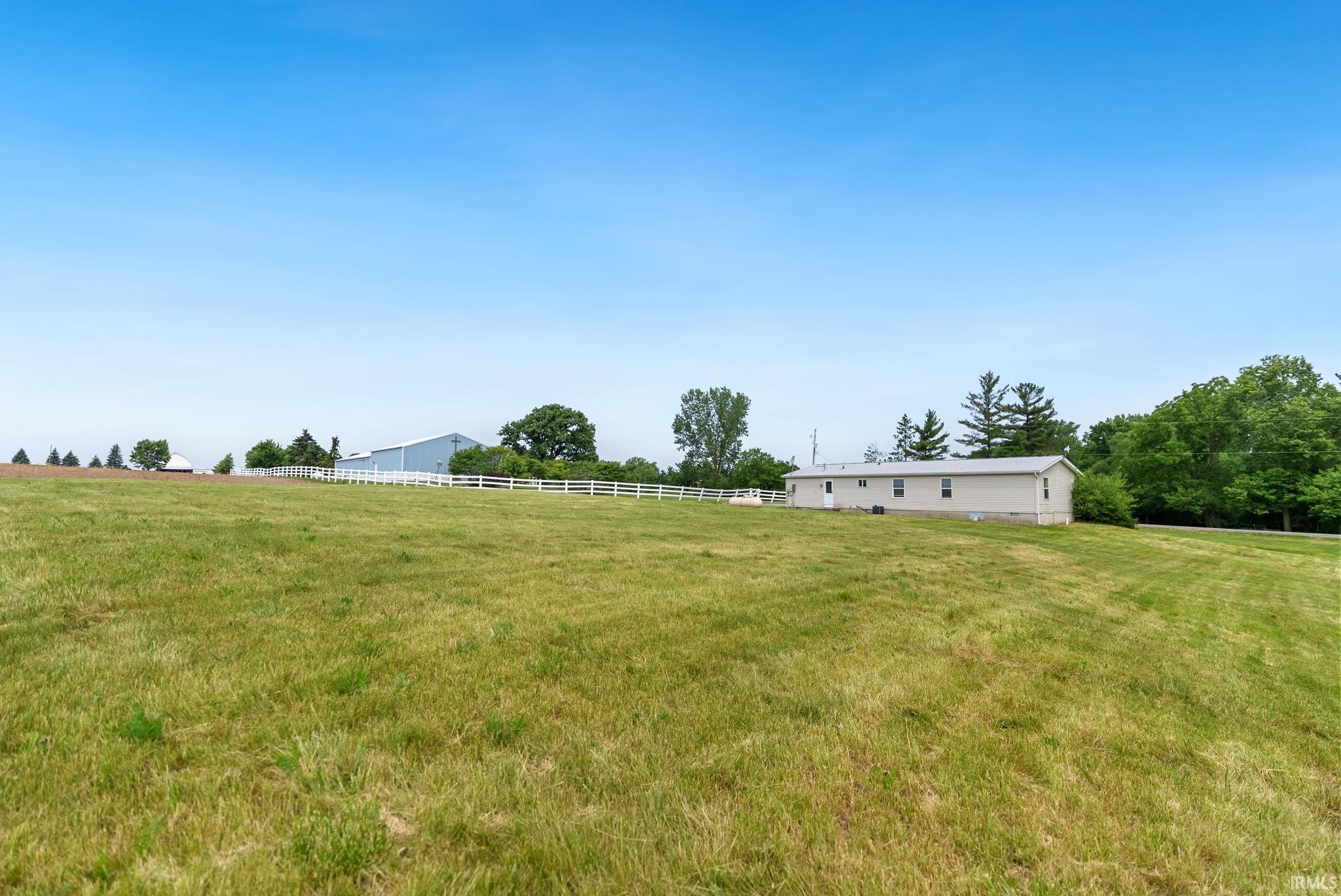 Expansive grassy terrain with a distant single-story structure and perimeter fencing