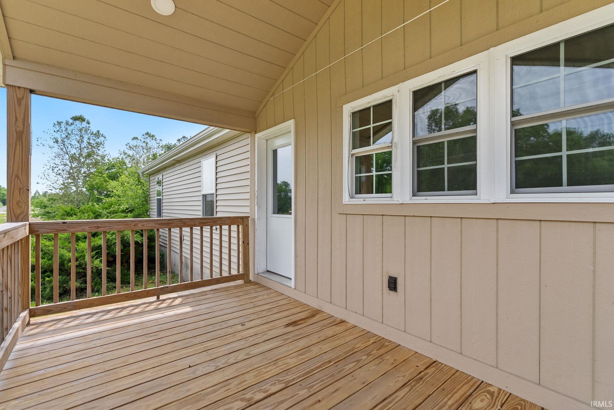 Covered outdoor deck with natural wood flooring and railing