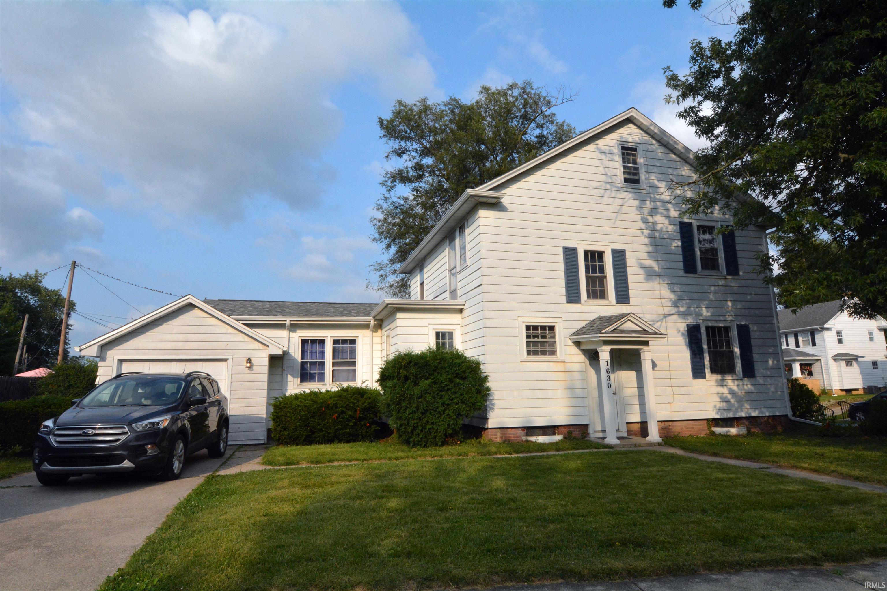 Two-story residence featuring light-colored siding, a covered front entry, and a single-car garage with an attached driveway