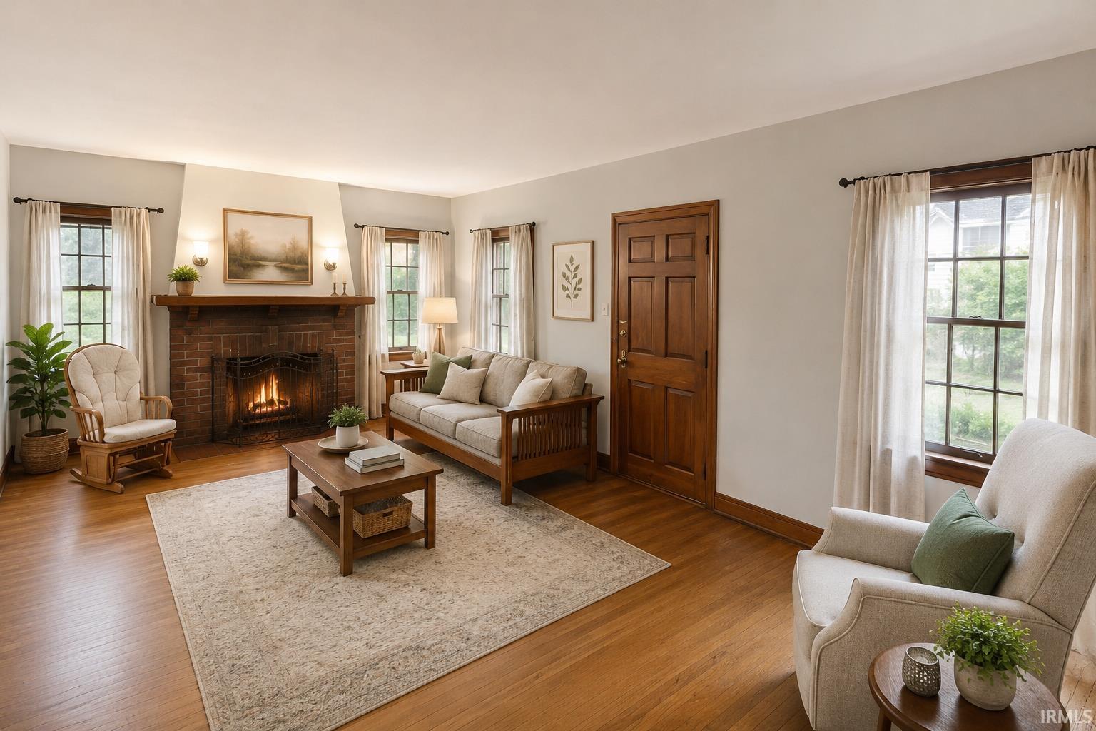 Living area featuring a brick fireplace with a wood mantel, wood-finish flooring, and multiple multi-pane windows