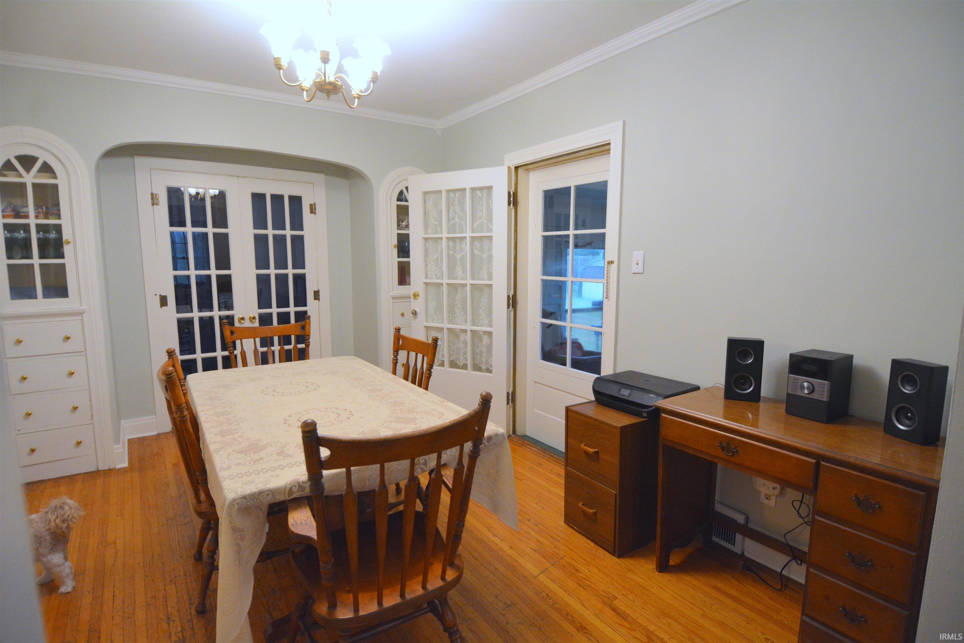 Spacious room featuring wood-finish flooring, two sets of French doors, and built-in white cabinetry with glass display tops
