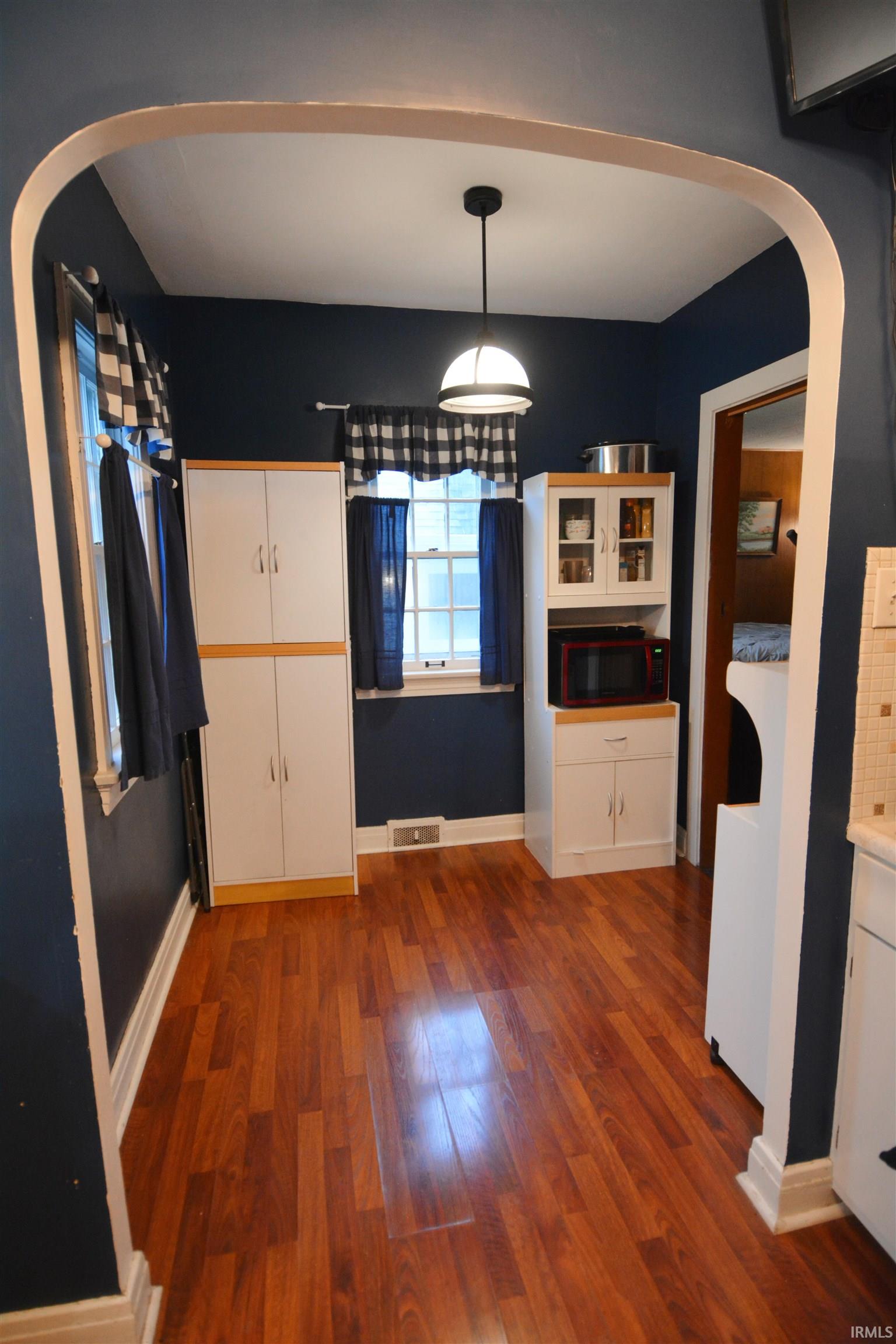 Arched entry framing a room with wood-finish flooring