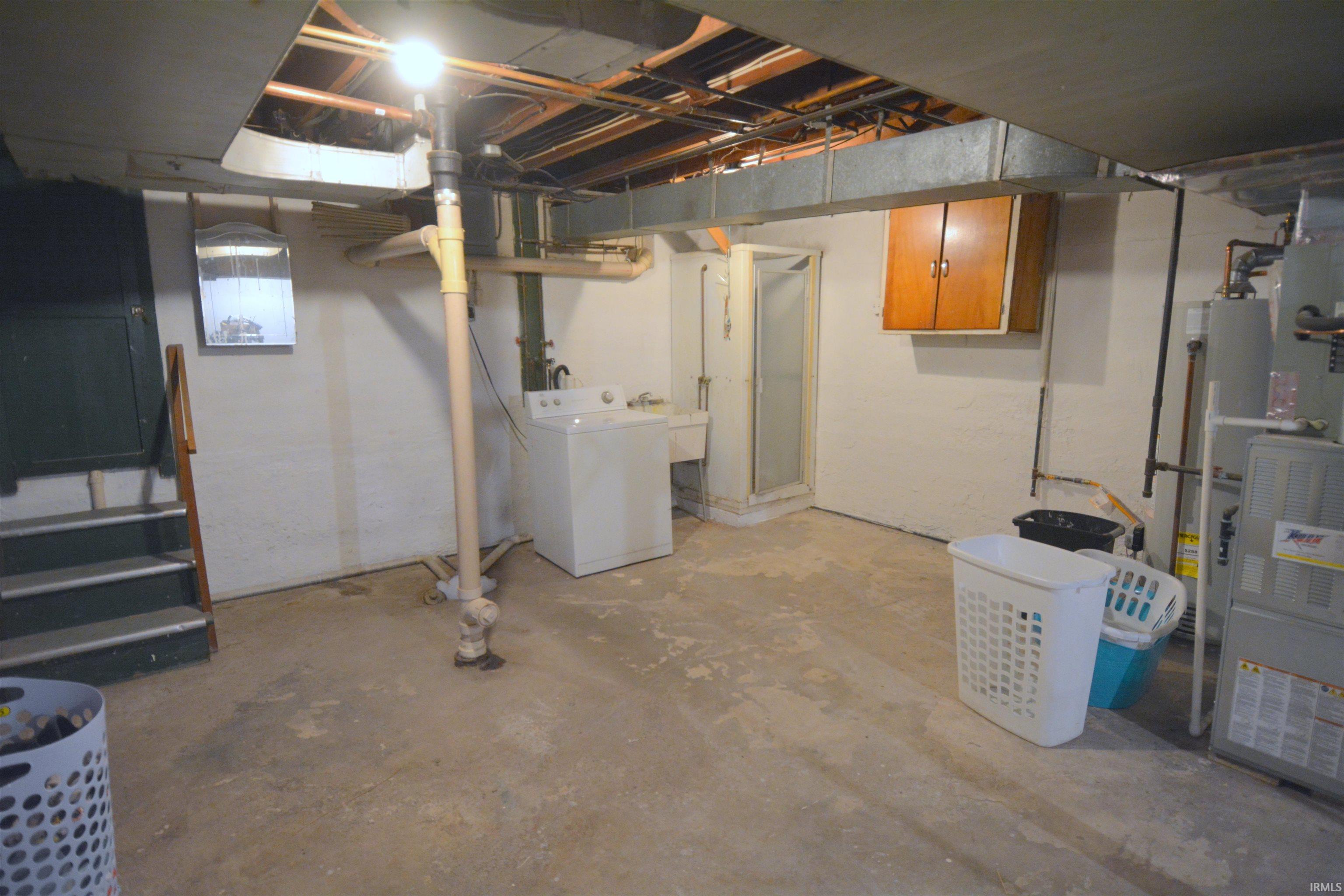 Unfinished basement area featuring a concrete floor, exposed ceiling joists, and visible utility infrastructure including ductwork and plumbing