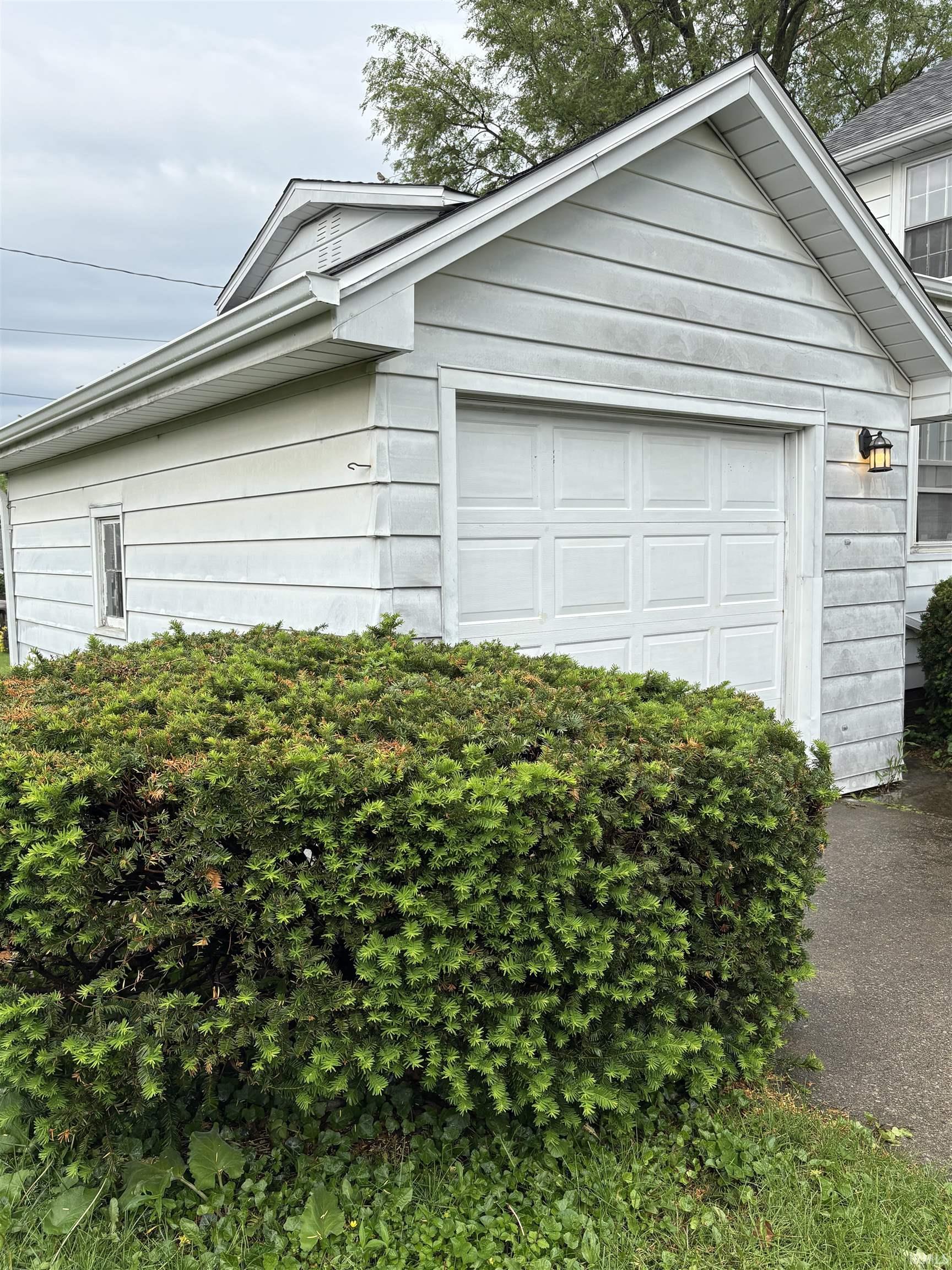 Detached garage featuring panel siding and an overhead door