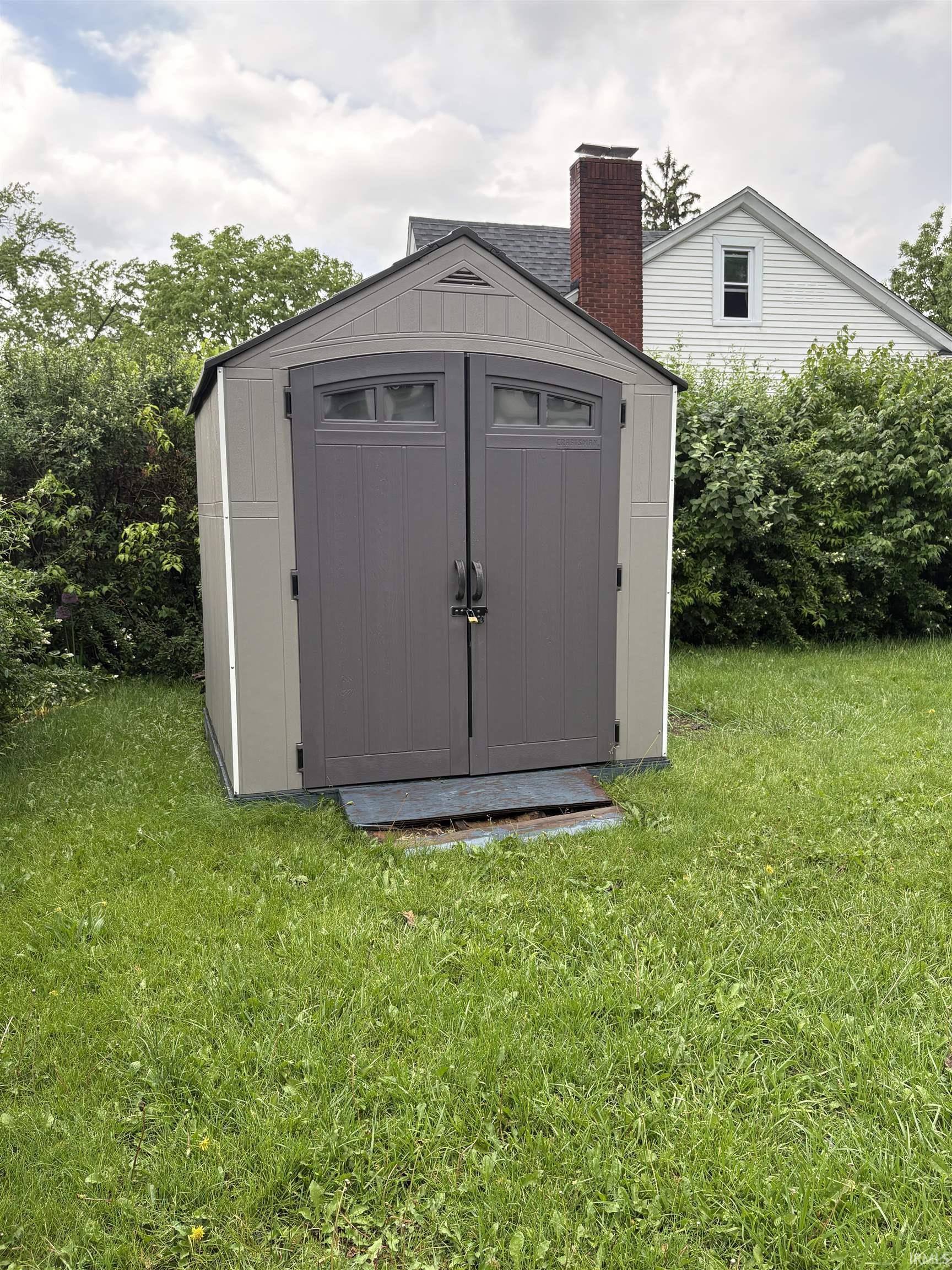 Freestanding outdoor storage shed featuring a dual-tone exterior with a light siding and dark-paneled doors