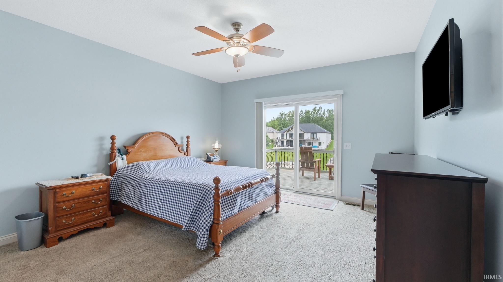 Bedroom featuring light blue walls, light-toned carpet, and a ceiling fan with integrated lighting