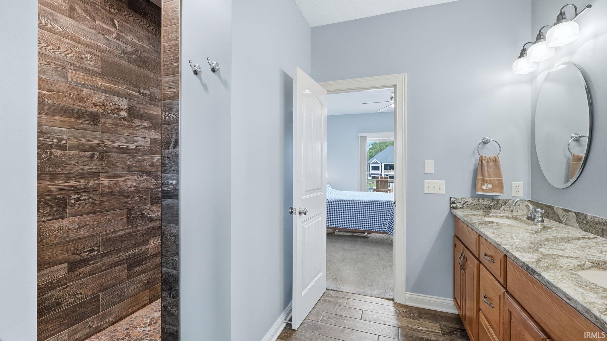 Double vanity with light-toned countertop, wood-finish cabinetry, and an oval mirror