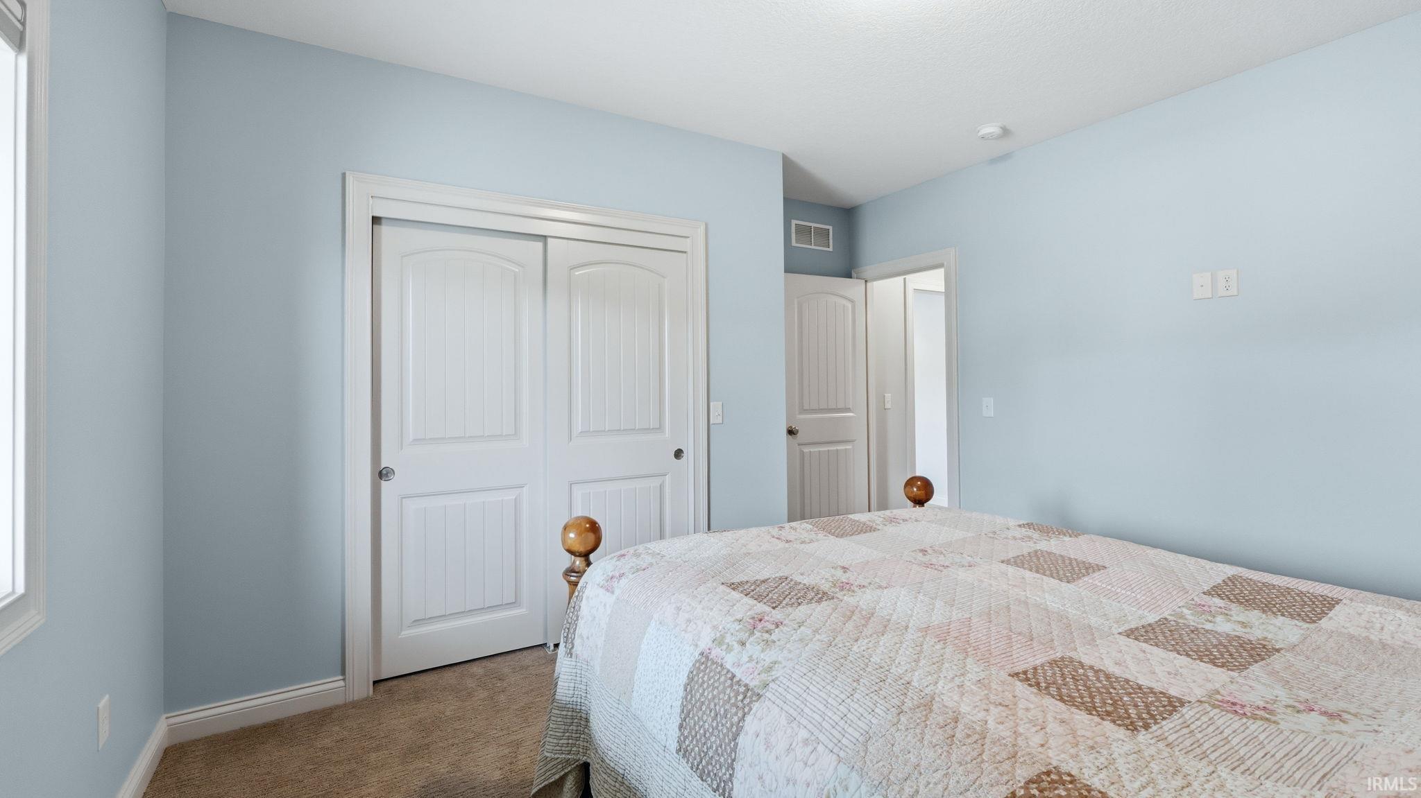 Bedroom featuring light blue walls, carpeted flooring, white baseboards, and a window with white trim