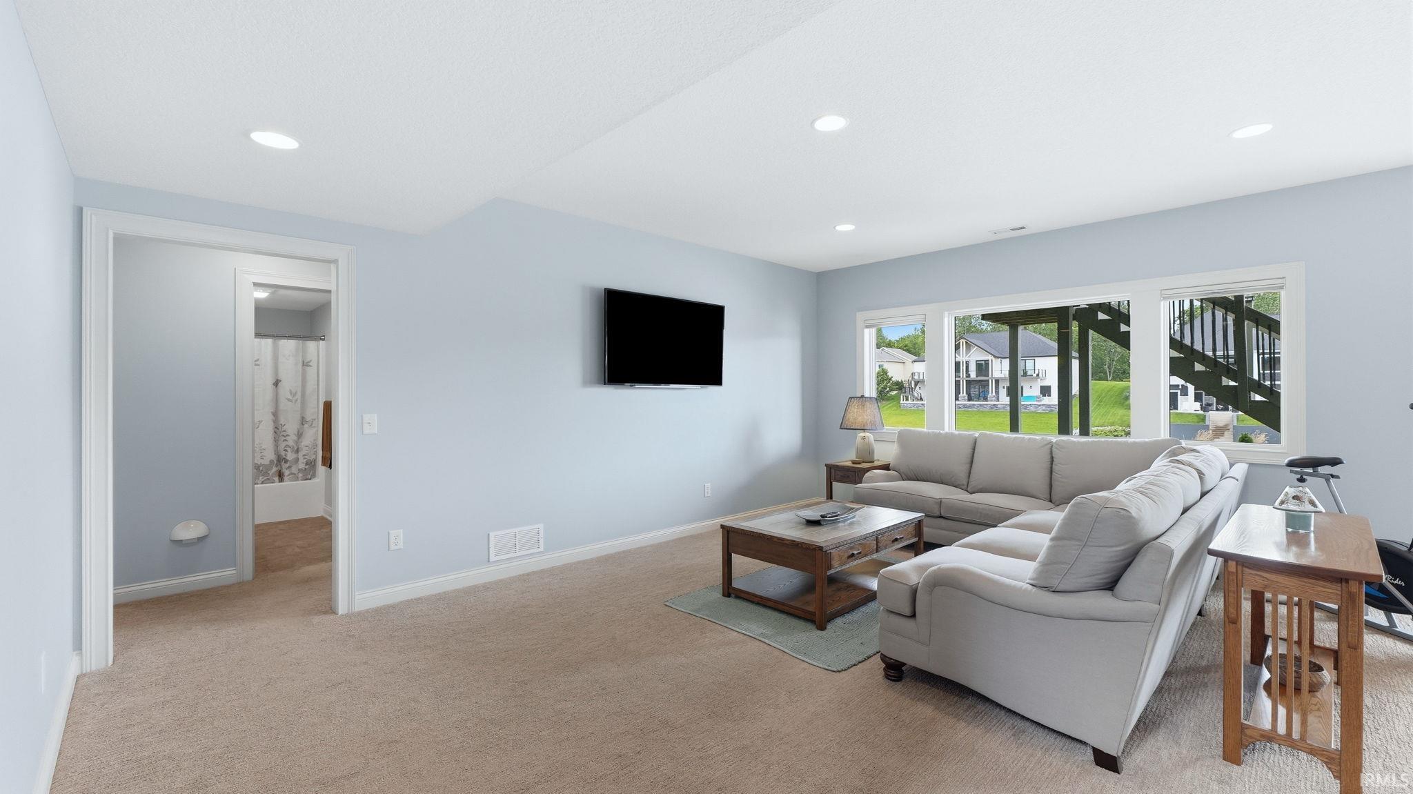 Carpeted recreation room featuring light blue walls, recessed lighting, and a wall-mounted television