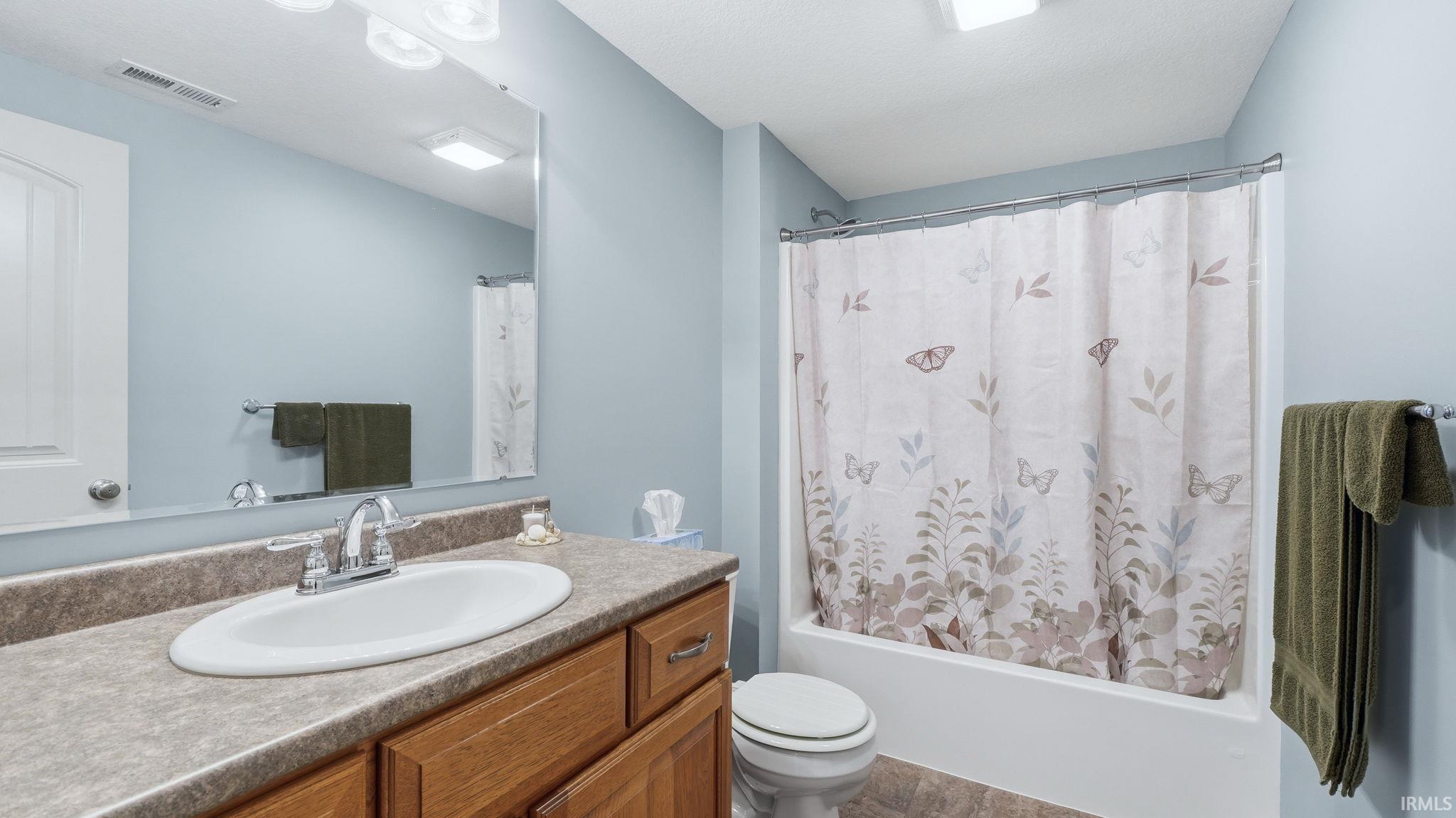 Bathroom featuring a wood-finish vanity with a laminate countertop, an oval undermount sink, and a chrome faucet