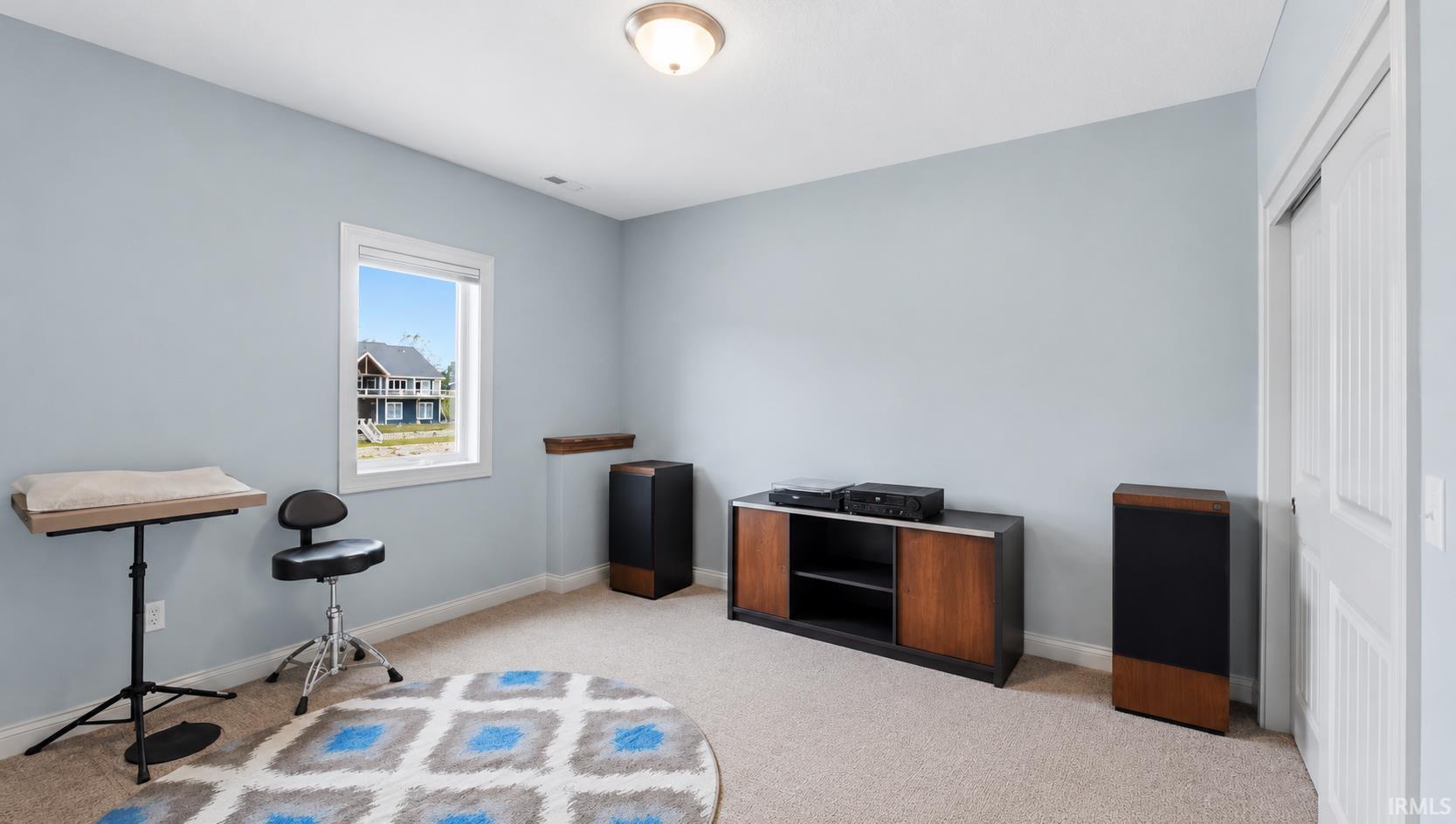 Room featuring light blue walls, plush carpet flooring, and a single window offering exterior views