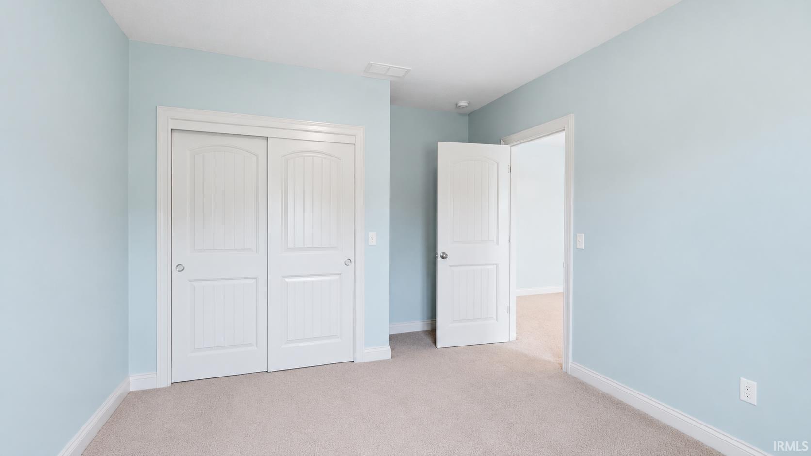 Interior room featuring light blue walls, white trim, and light-colored carpet