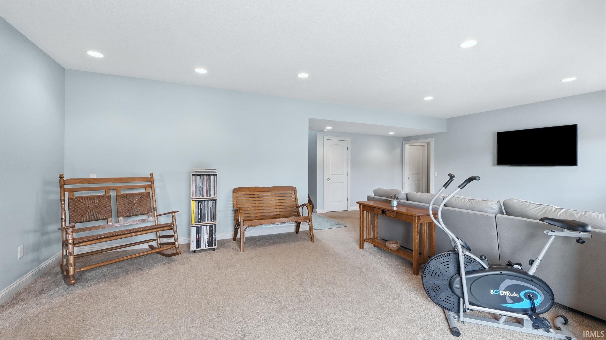 Spacious room featuring light blue walls, recessed lighting, and neutral-toned carpeting