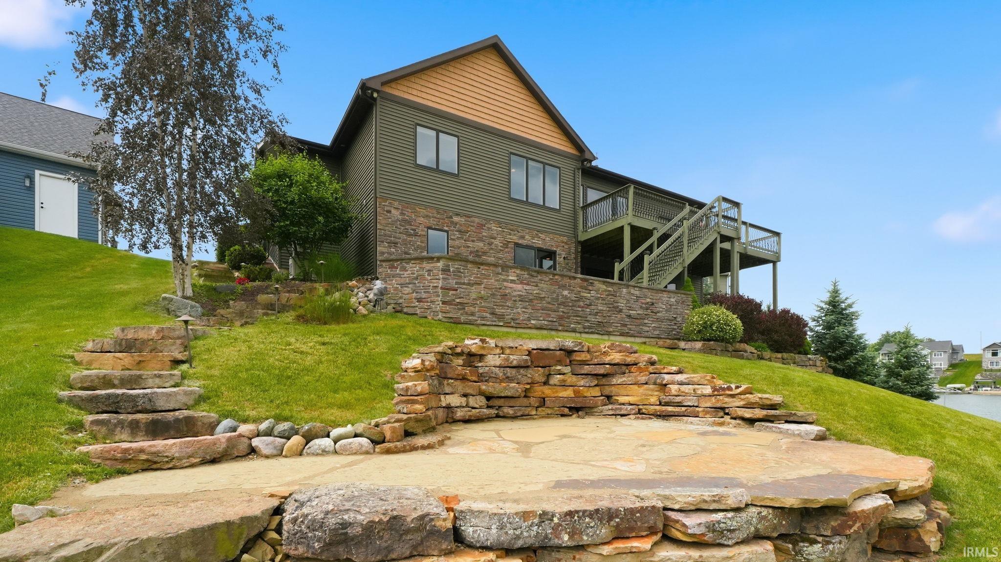Stone patio with tiered retaining walls, natural stone steps, and sloped lawn