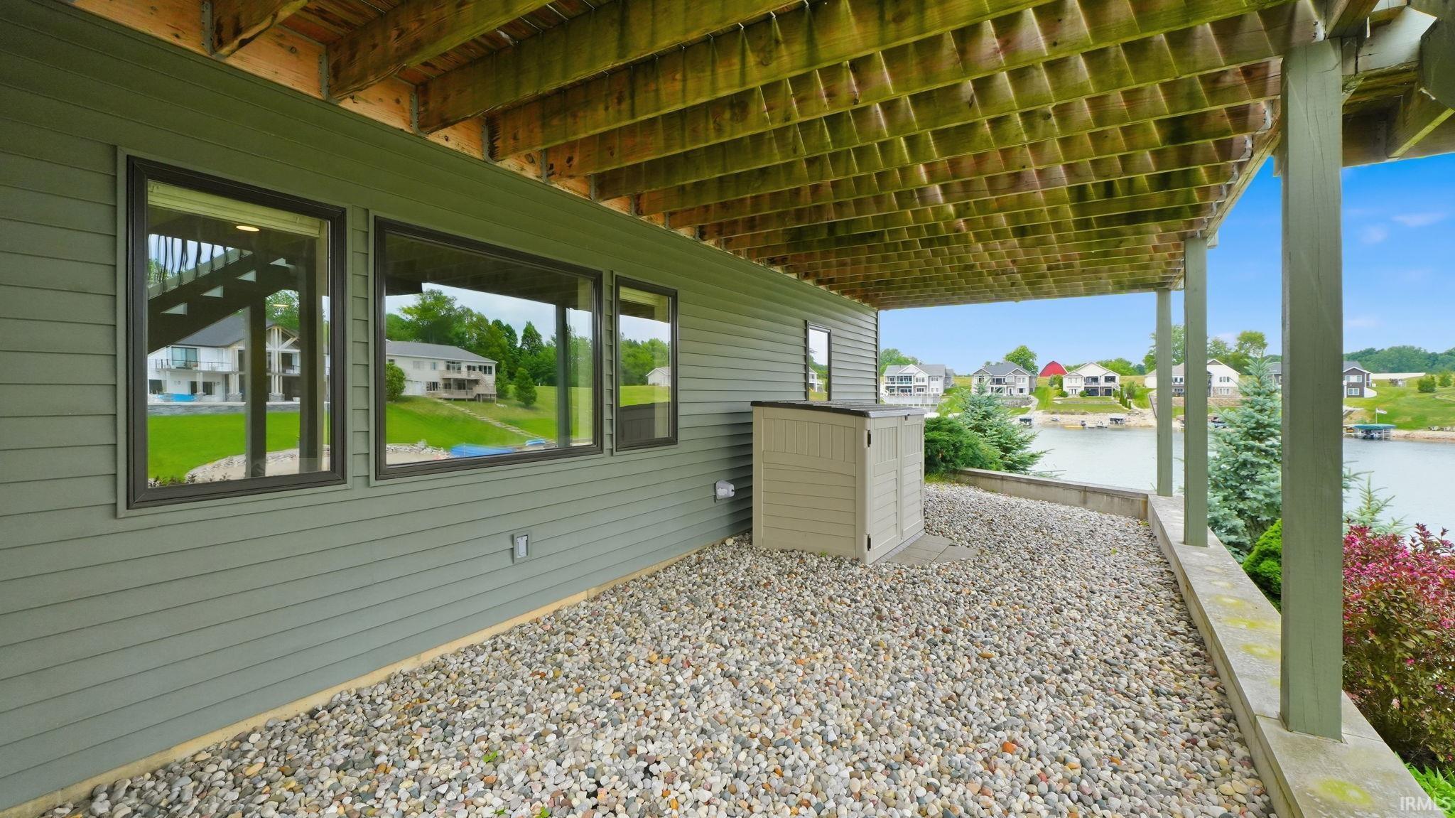 Covered patio space featuring a gravel surface and exposed wood ceiling