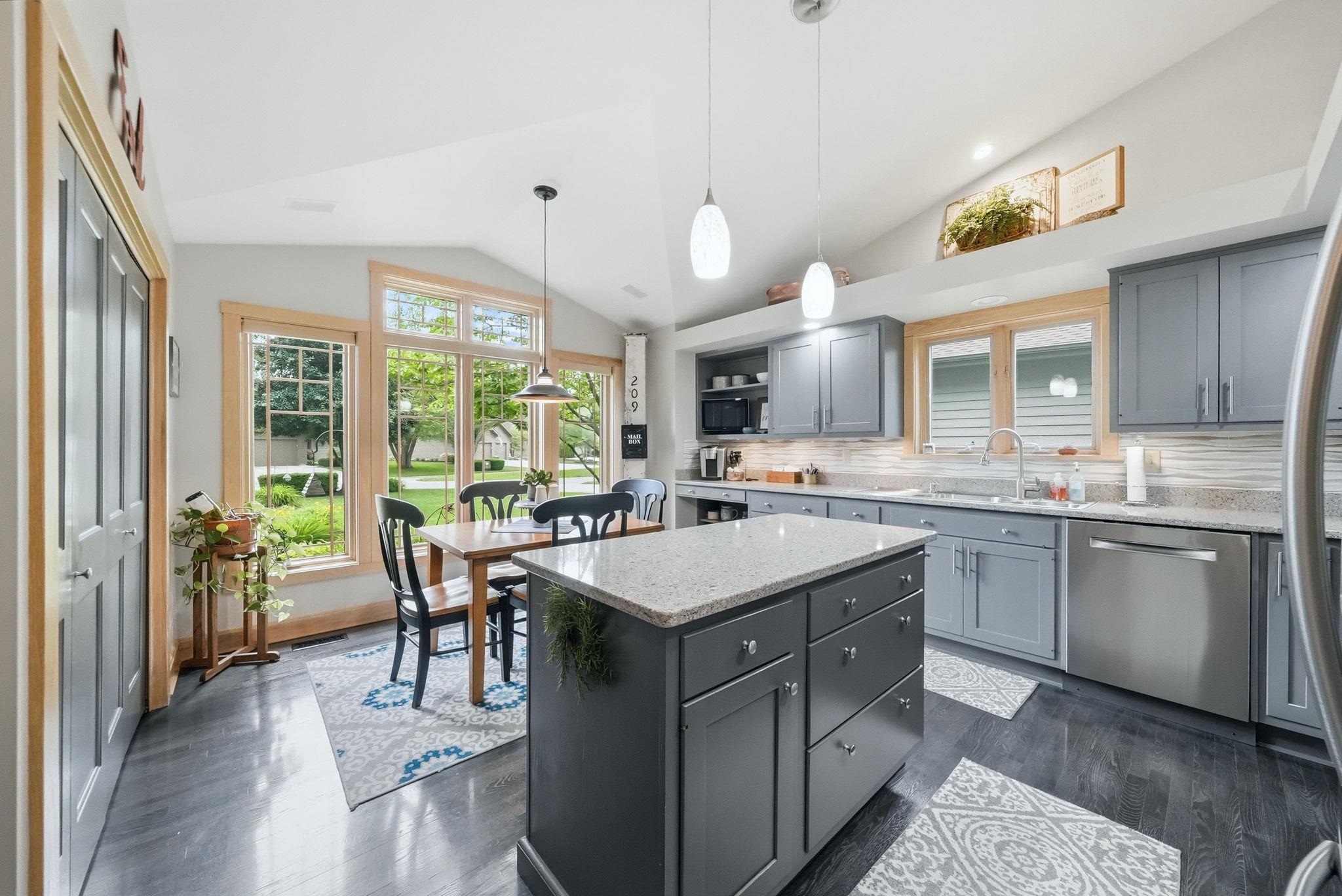 Open-concept kitchen and dining area featuring a vaulted ceiling and dark wood-finish flooring