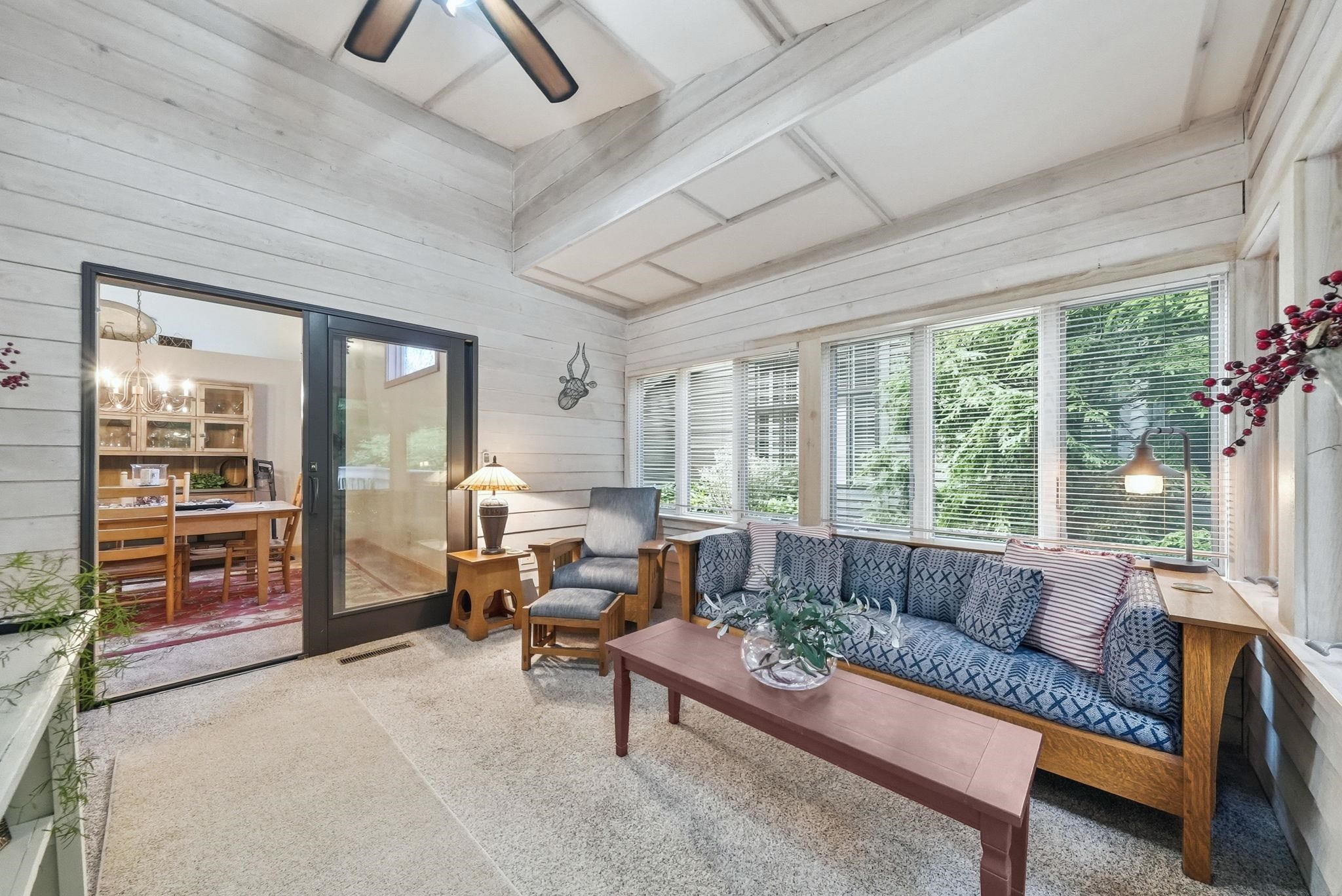 Sunroom with shiplap walls and ceiling, featuring a ceiling fan, multiple windows with blinds, and sliding glass doors