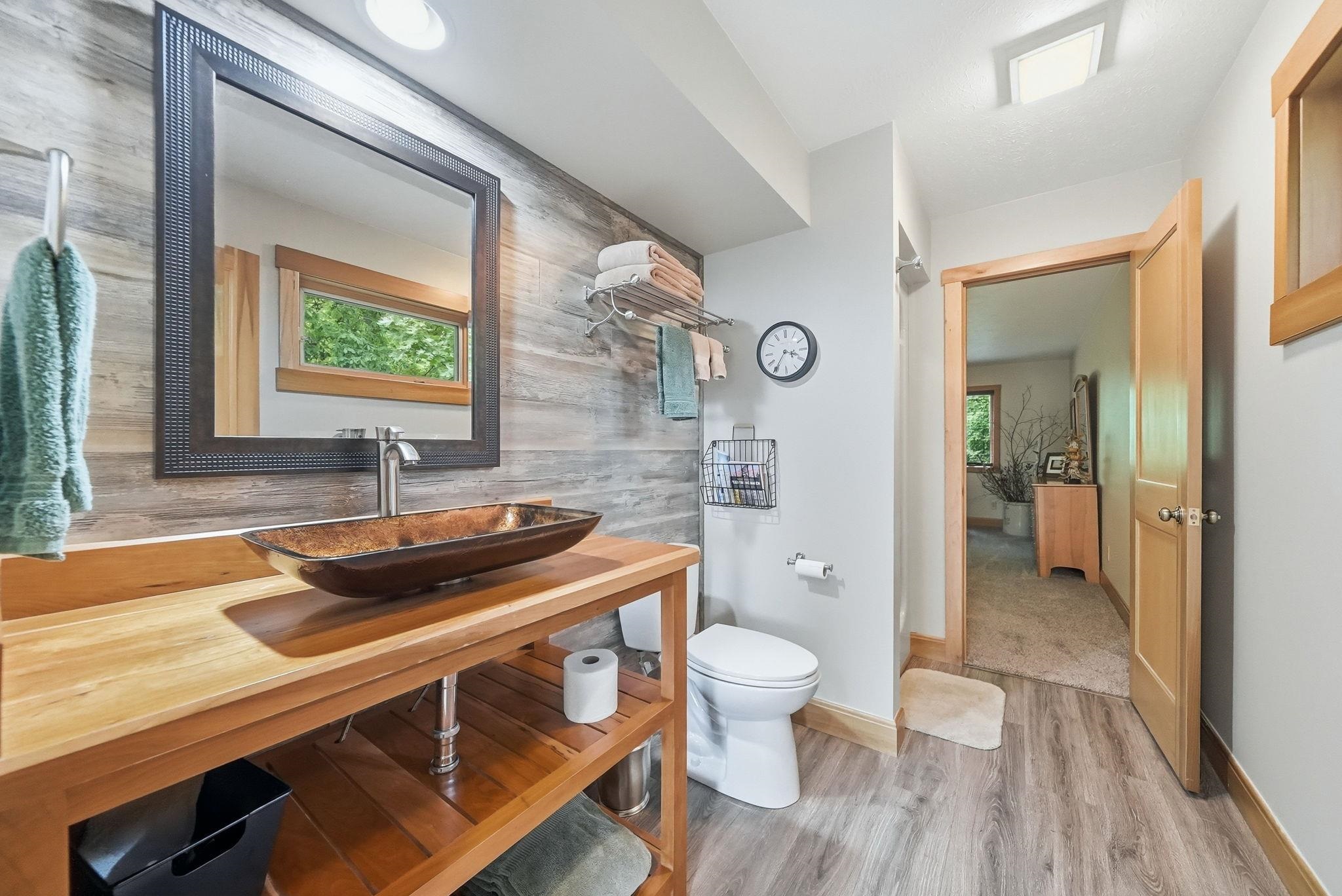 Bathroom featuring a floating wood vanity with a vessel sink, a framed mirror, and wood-finish flooring