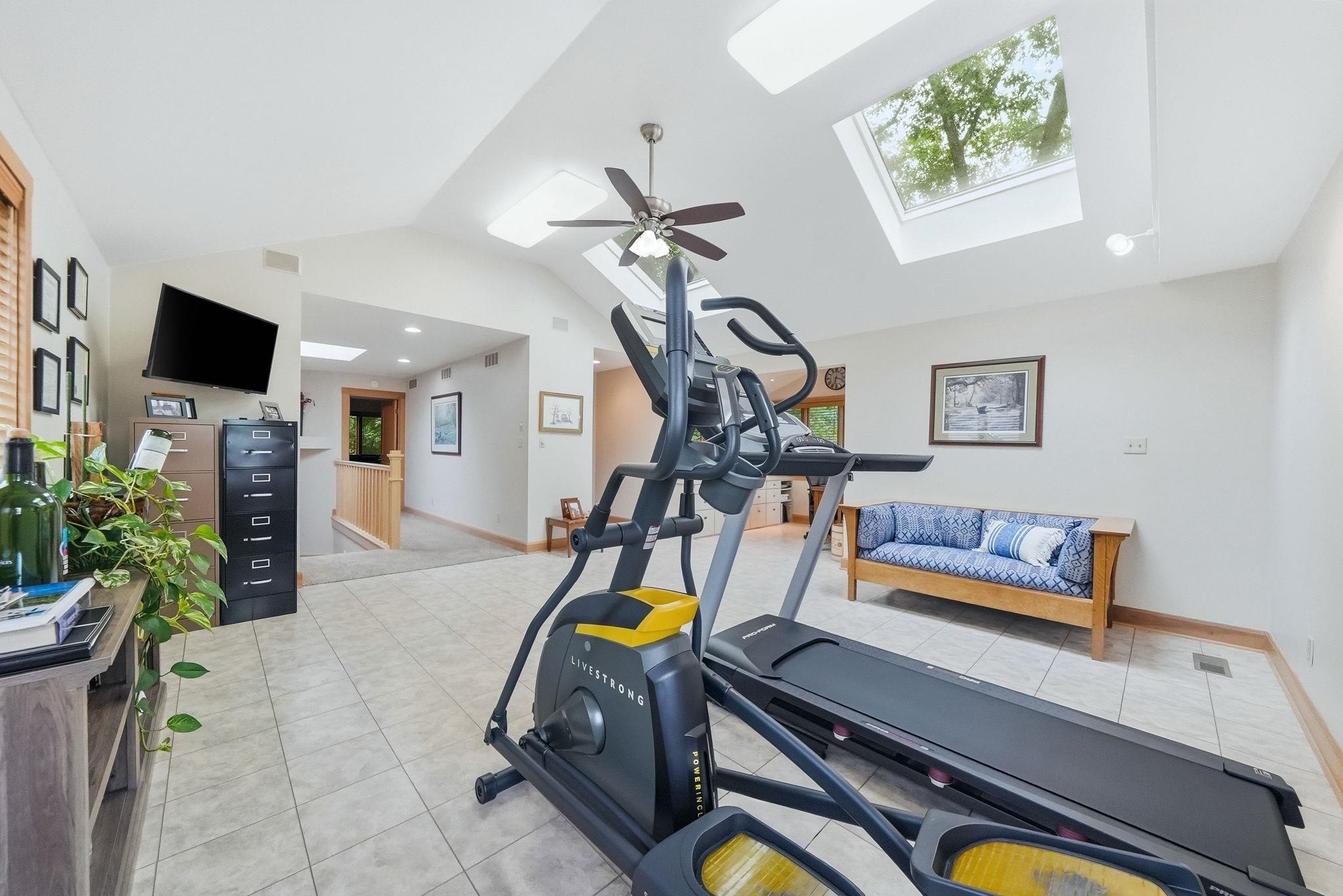 Spacious room featuring vaulted ceilings, multiple skylights, and tile flooring