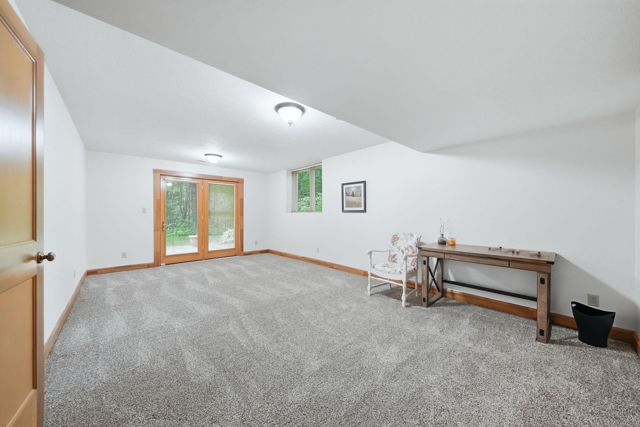 Spacious room featuring light-colored carpeting, white walls, and warm wood trim