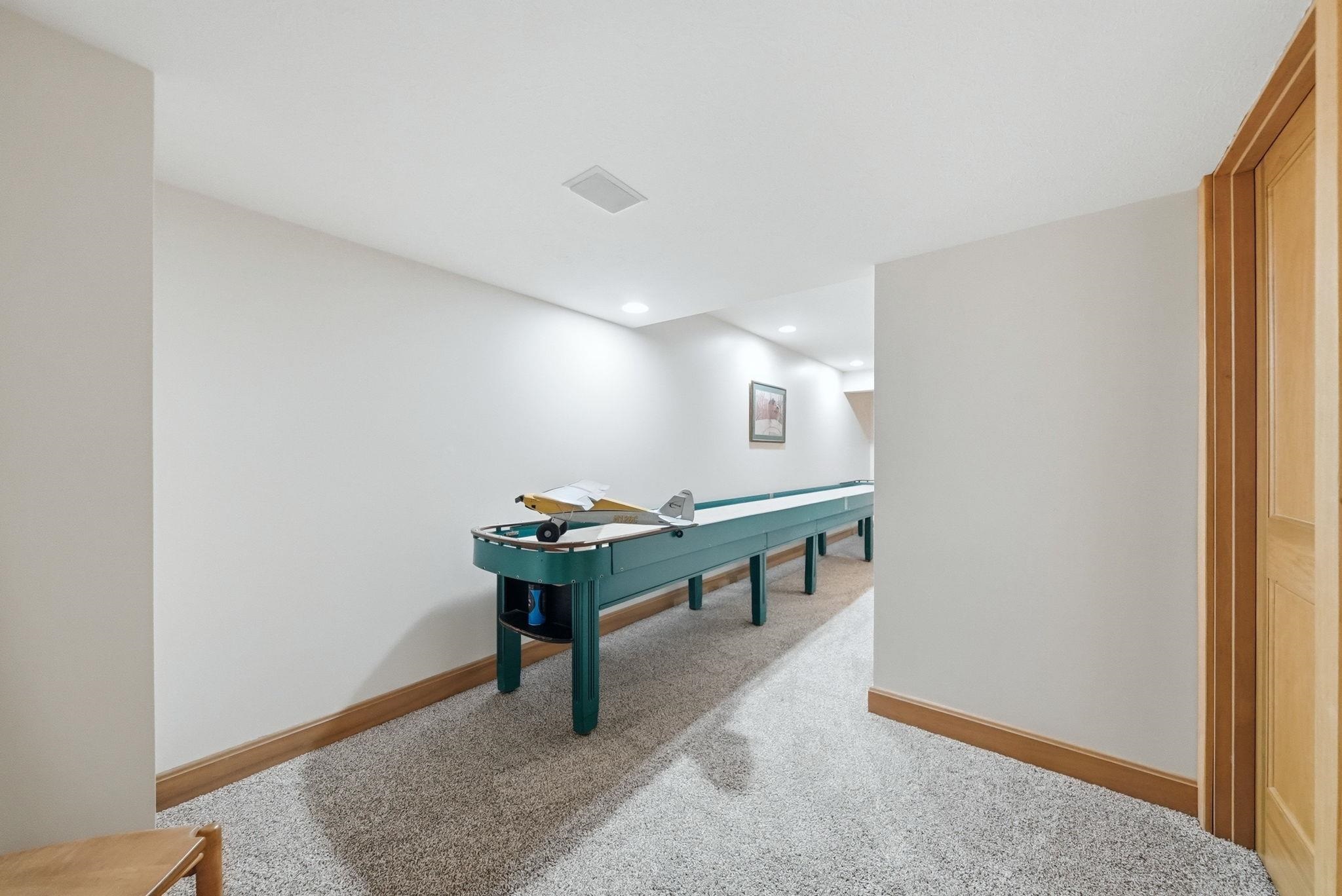 Carpeted hallway featuring white walls, light wood trim, recessed lighting, and a light wood door frame