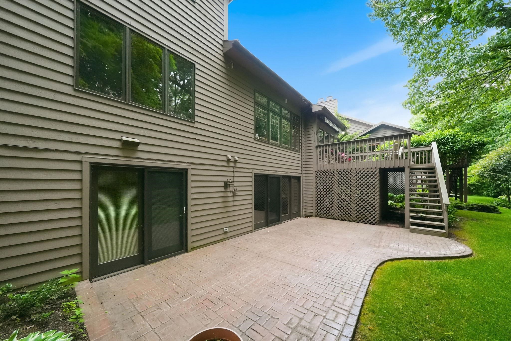 Stained wood siding exterior featuring a multi-level deck with lattice skirting and a lower-level stamped concrete patio