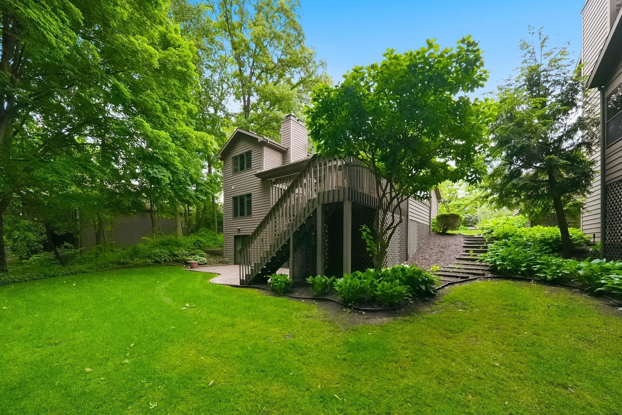 Rear exterior with wood siding, a multi-level wooden deck, and a ground-level patio