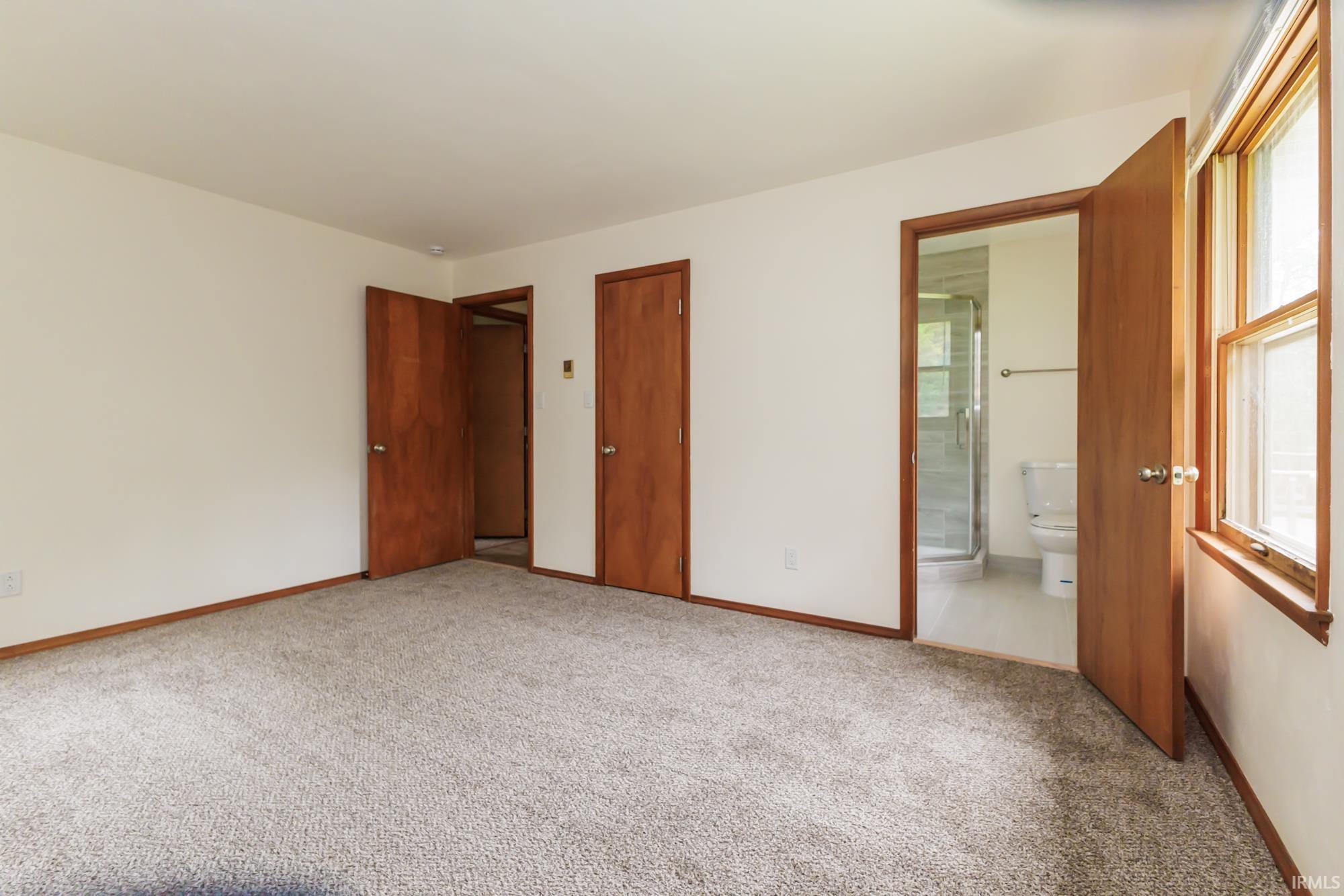 Carpeted interior room featuring light-toned walls, wood-finish doors, and matching wood-finish trim