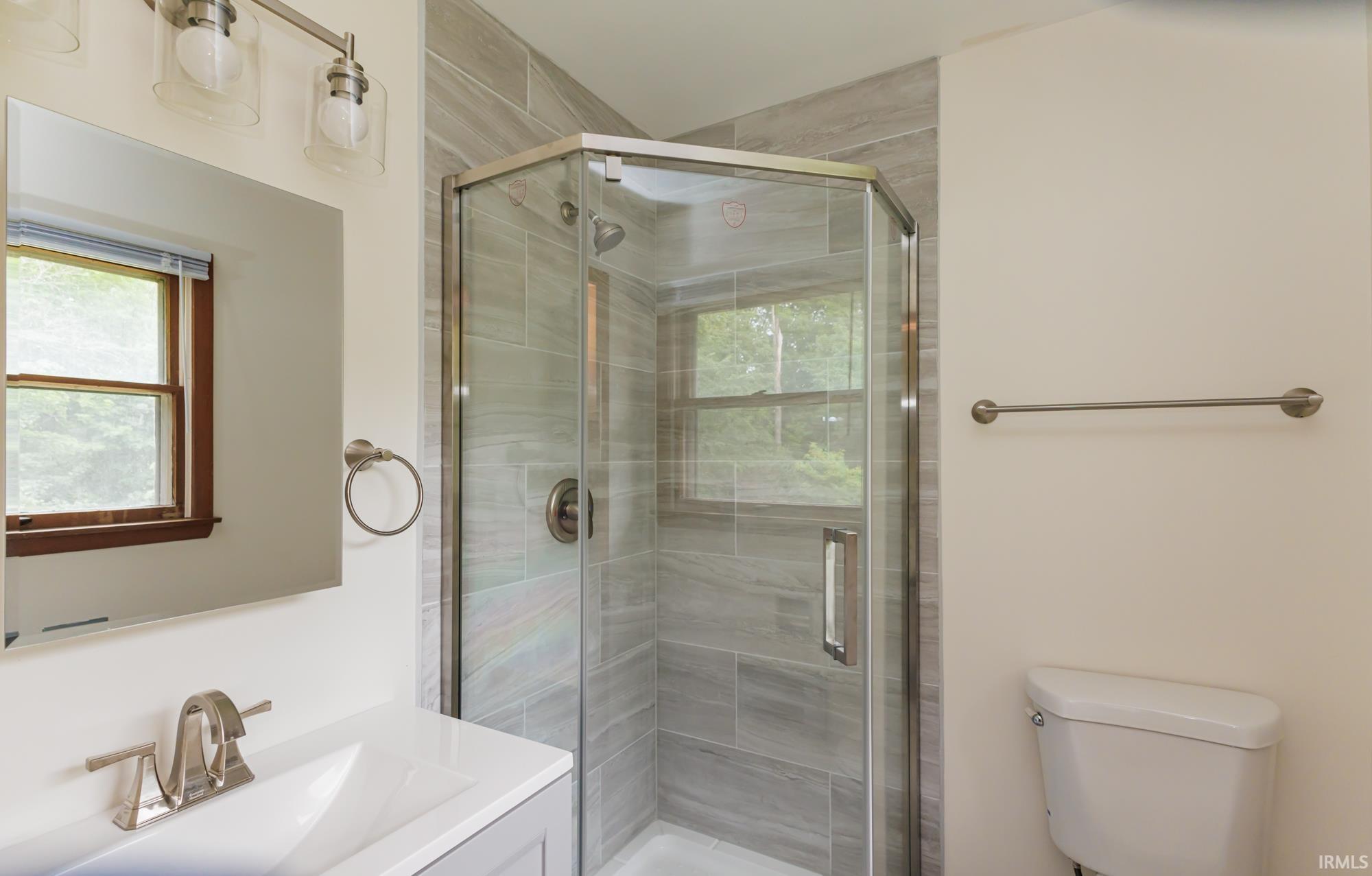 Glass-enclosed shower with horizontal tile surround and brushed nickel fixtures