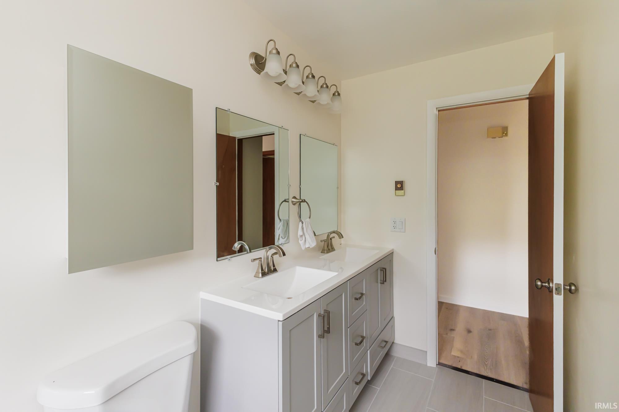 Bathroom featuring a double vanity with light gray cabinetry, white countertops, and dual rectangular sinks