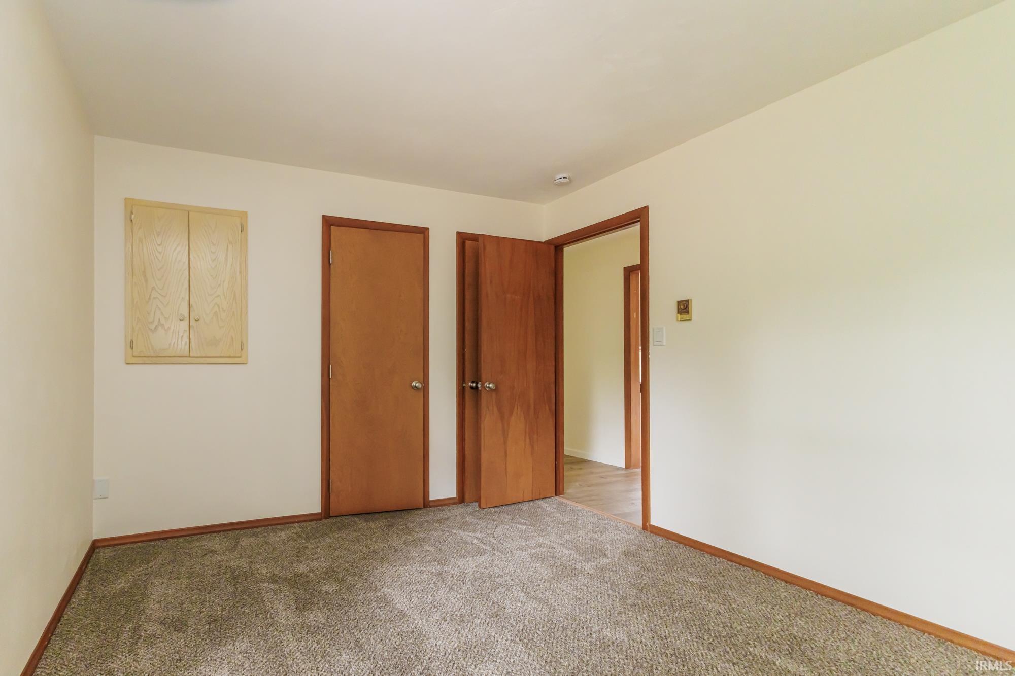 Neutral wall color with wood trim and matching doors, featuring a built-in wooden cabinet and carpeted flooring