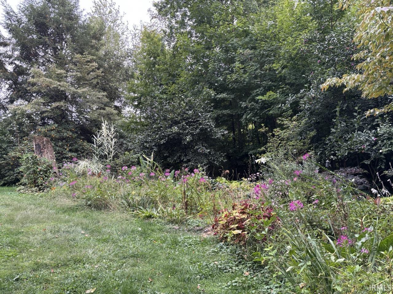 Landscaped perennial garden featuring a variety of flowering plants and mature trees