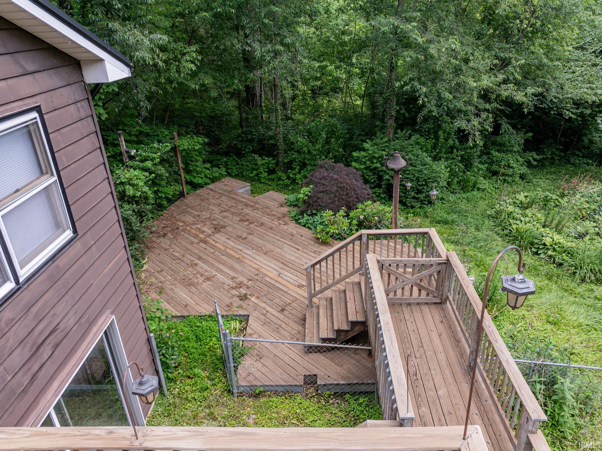 Multi-level wood deck featuring a landing and stairs, wood handrails, and chain-link fencing