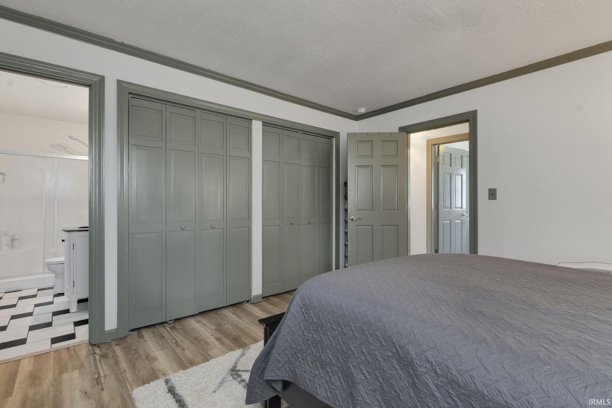 Bedroom featuring wood-finish flooring, two sets of bi-fold closet doors, and contrasting trim