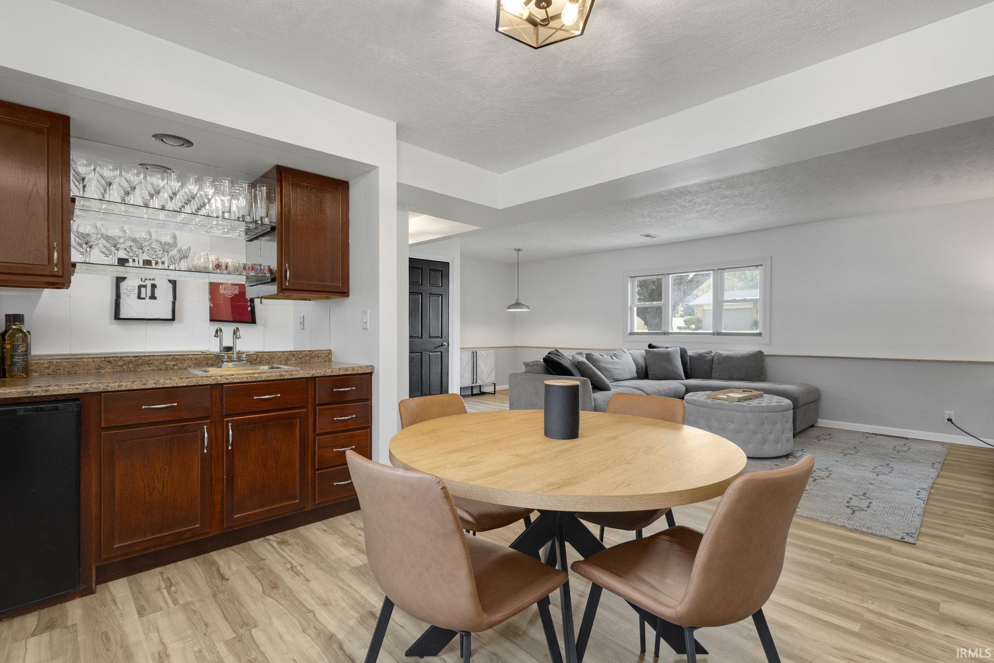Dedicated wet bar featuring wood-finish cabinetry, a built-in sink, and glass shelving