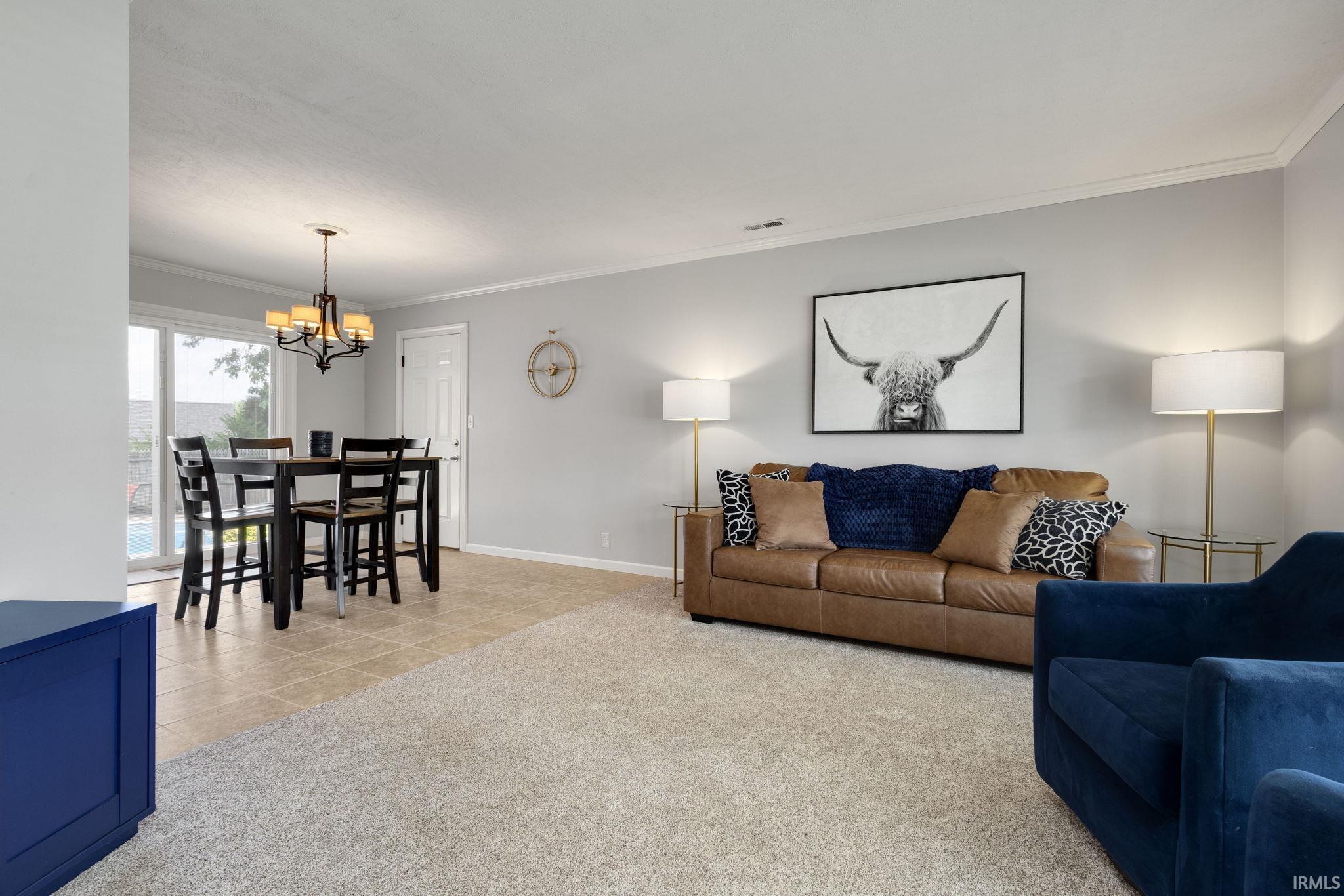 Open-concept living space featuring light-colored walls and crown molding