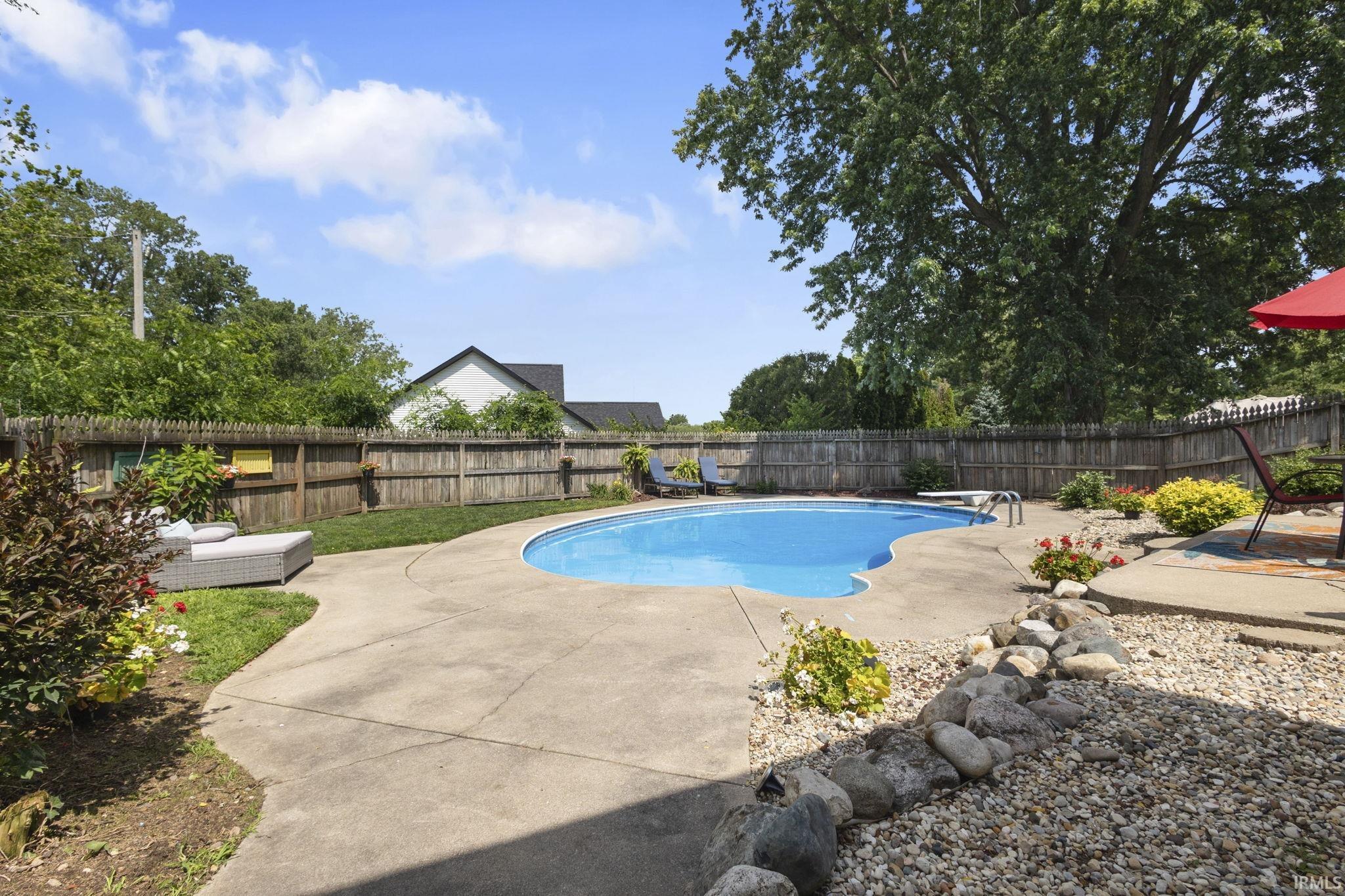 In-ground swimming pool with an irregular shape, concrete surround, and a diving board