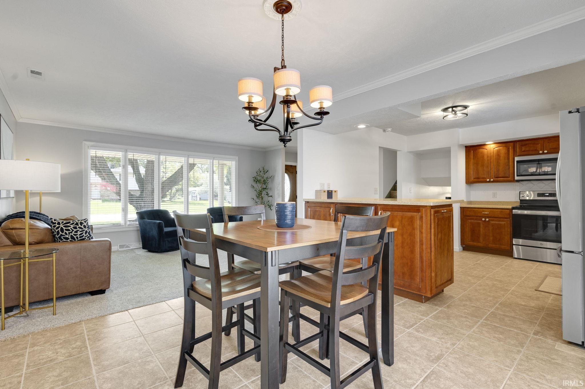 Bright dining area featuring a pendant light fixture, tile flooring, and a dining island
