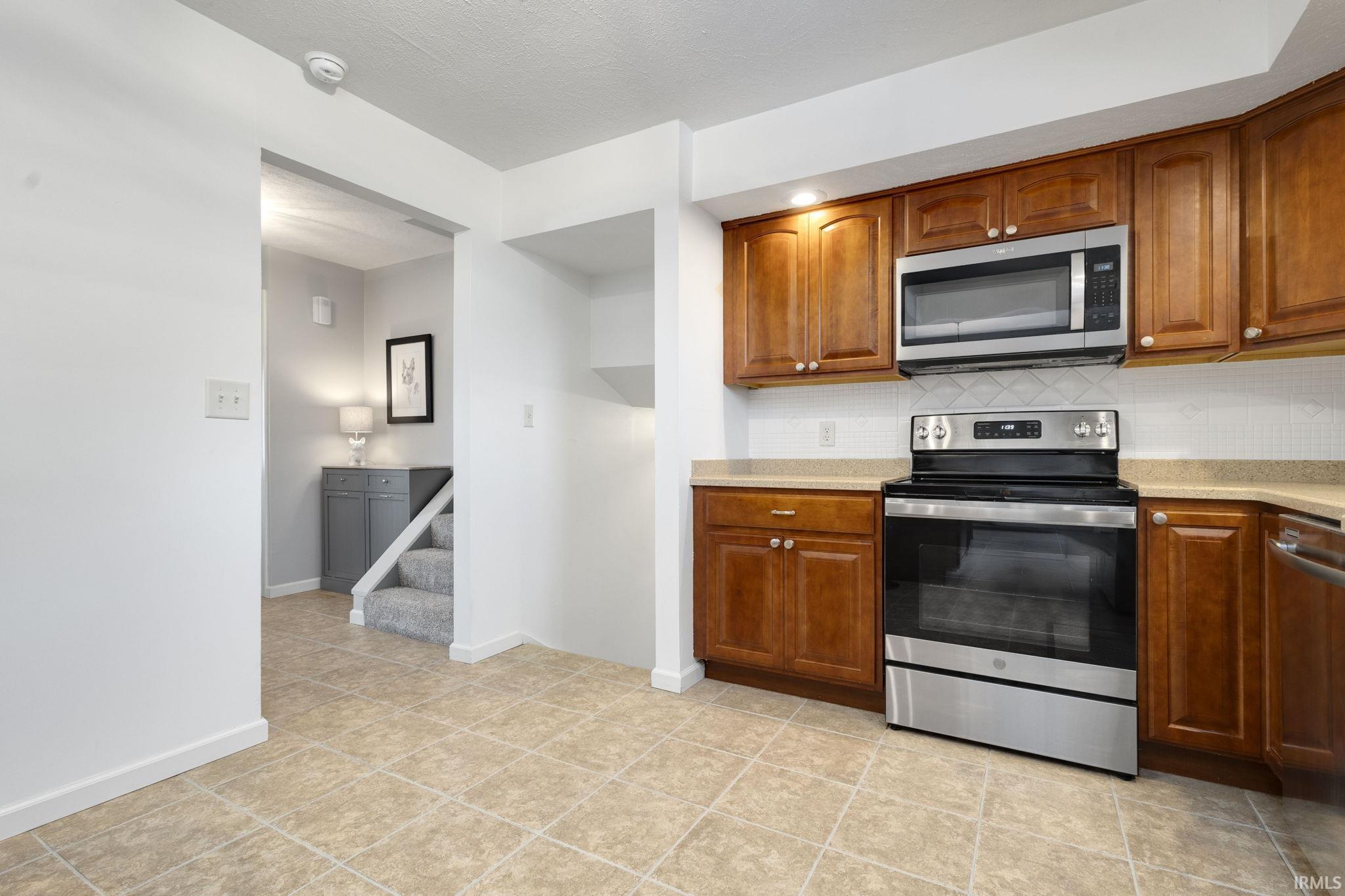 Kitchen featuring warm wood-finish cabinetry, stainless steel range, and stainless steel microwave