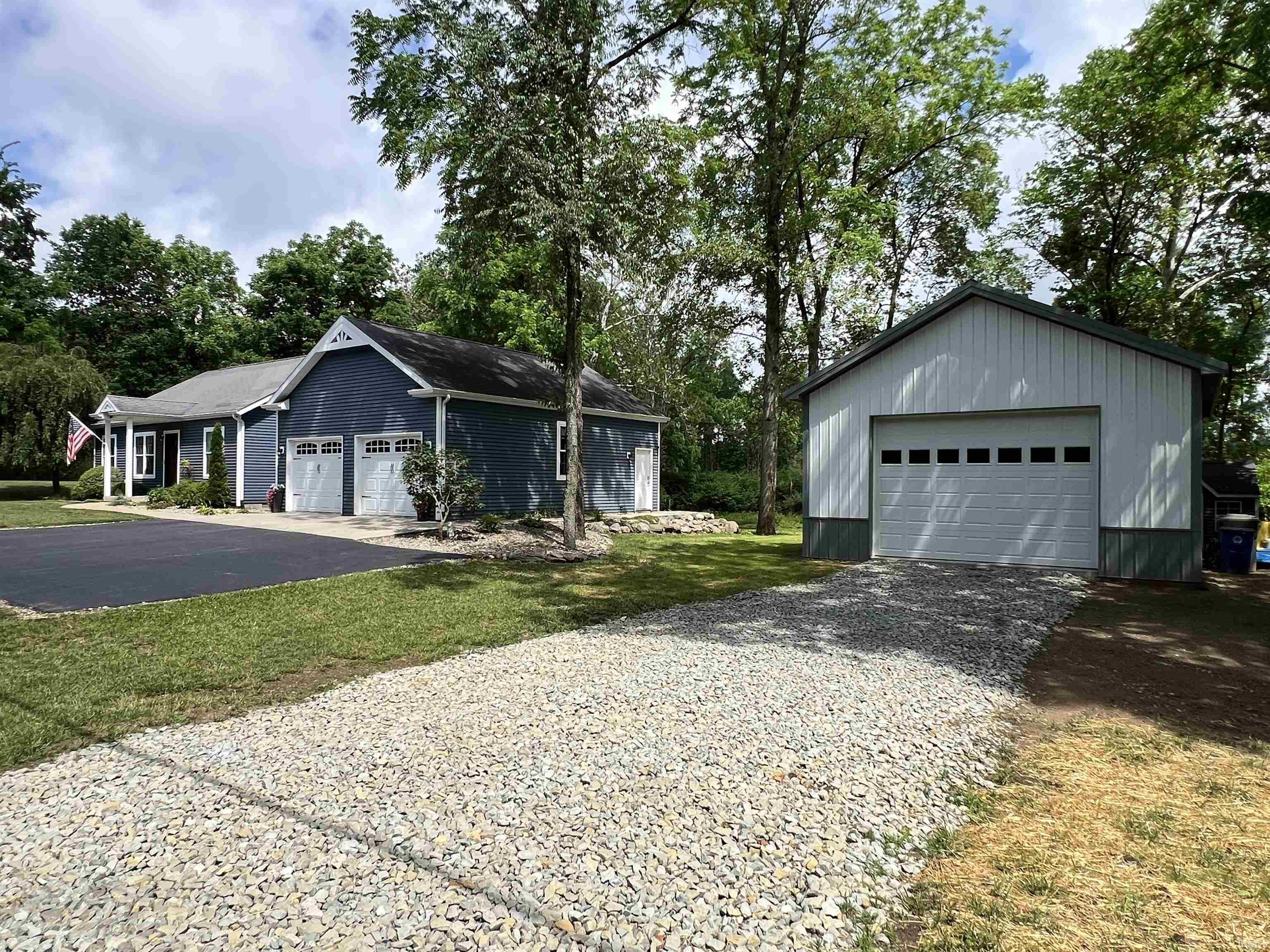 Detached garage building with a single overhead door, complemented by a main residence featuring blue siding, a covered entry, and an attached two-car garage