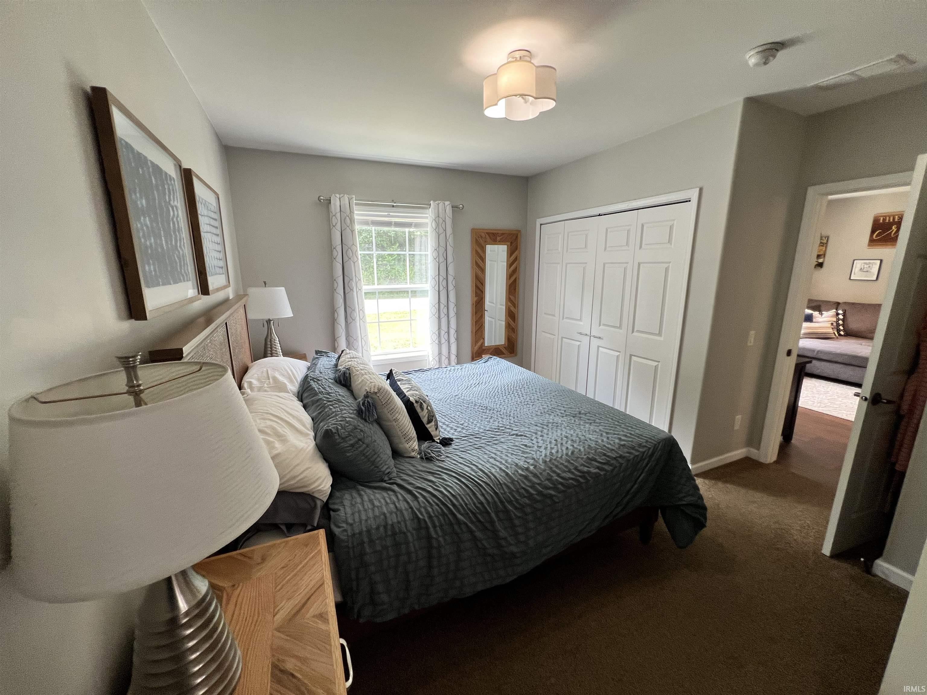 Bedroom featuring a window with exterior views, carpet flooring, a built-in closet with bi-fold doors, and a decorative ceiling light fixture