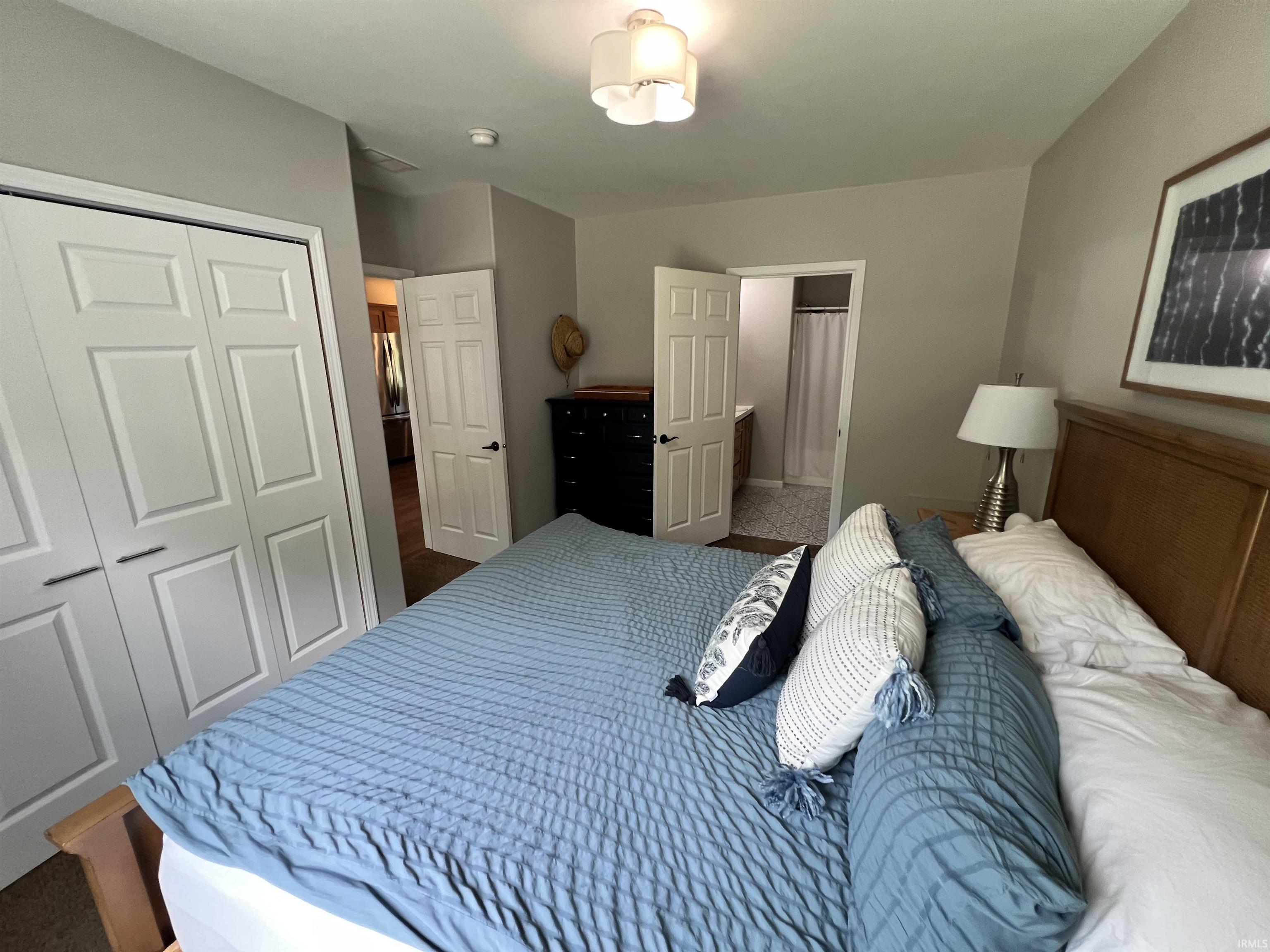 Bedroom featuring a light gray wall color, a contemporary ceiling light fixture, bi-fold closet doors with dark hardware, and wood-finish flooring