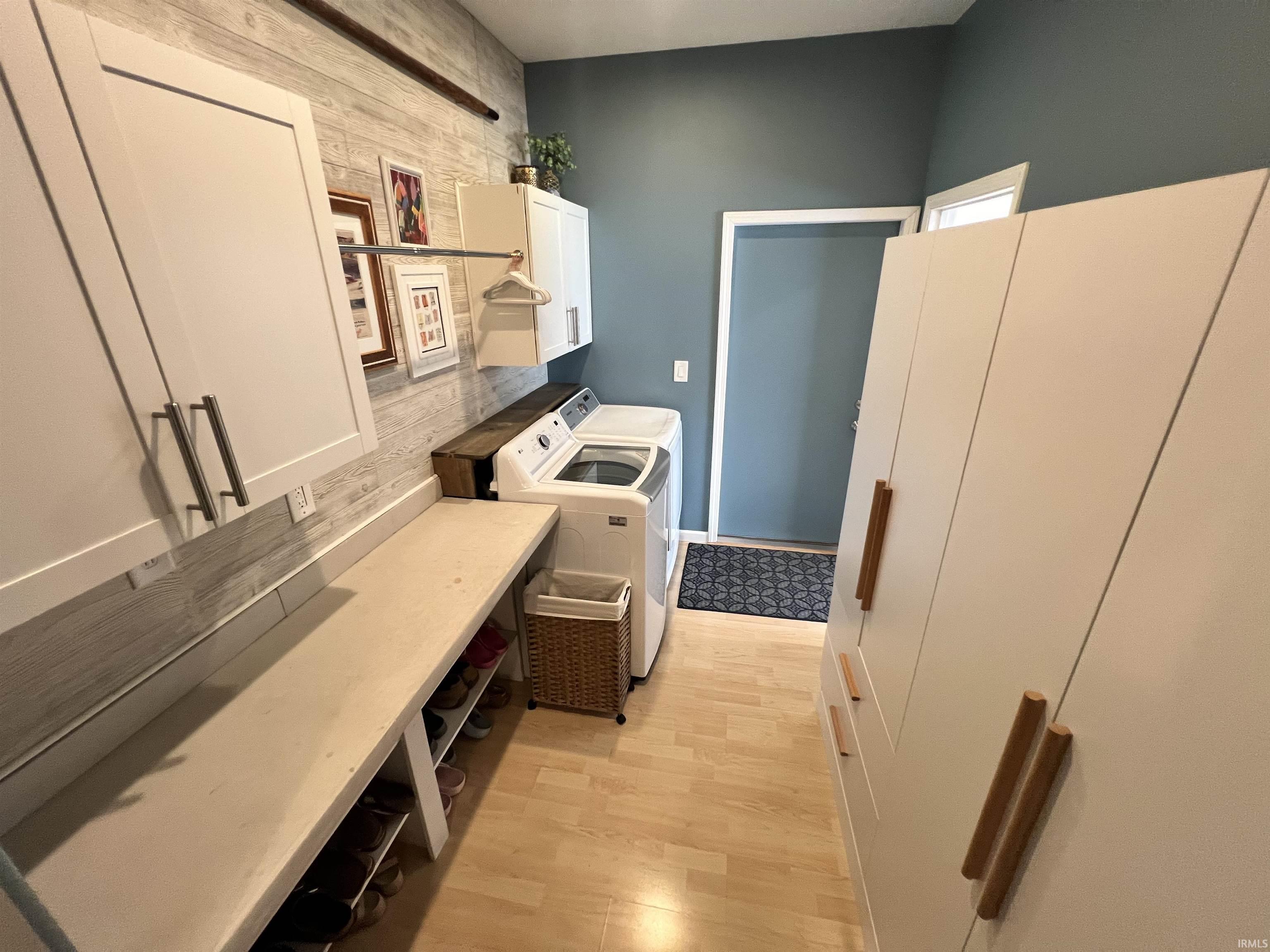 Utility room featuring wood-finish flooring, white cabinetry, integrated countertop with open shelving, and a wall-mounted drying rod