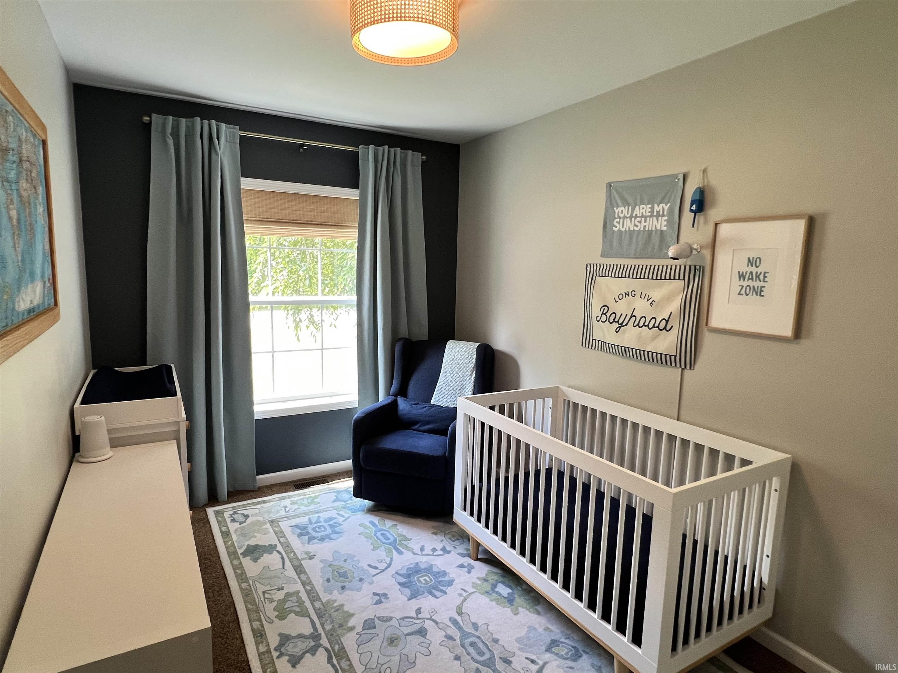 Room featuring warm neutral and accent walls, a window with natural light, and wood-finish flooring