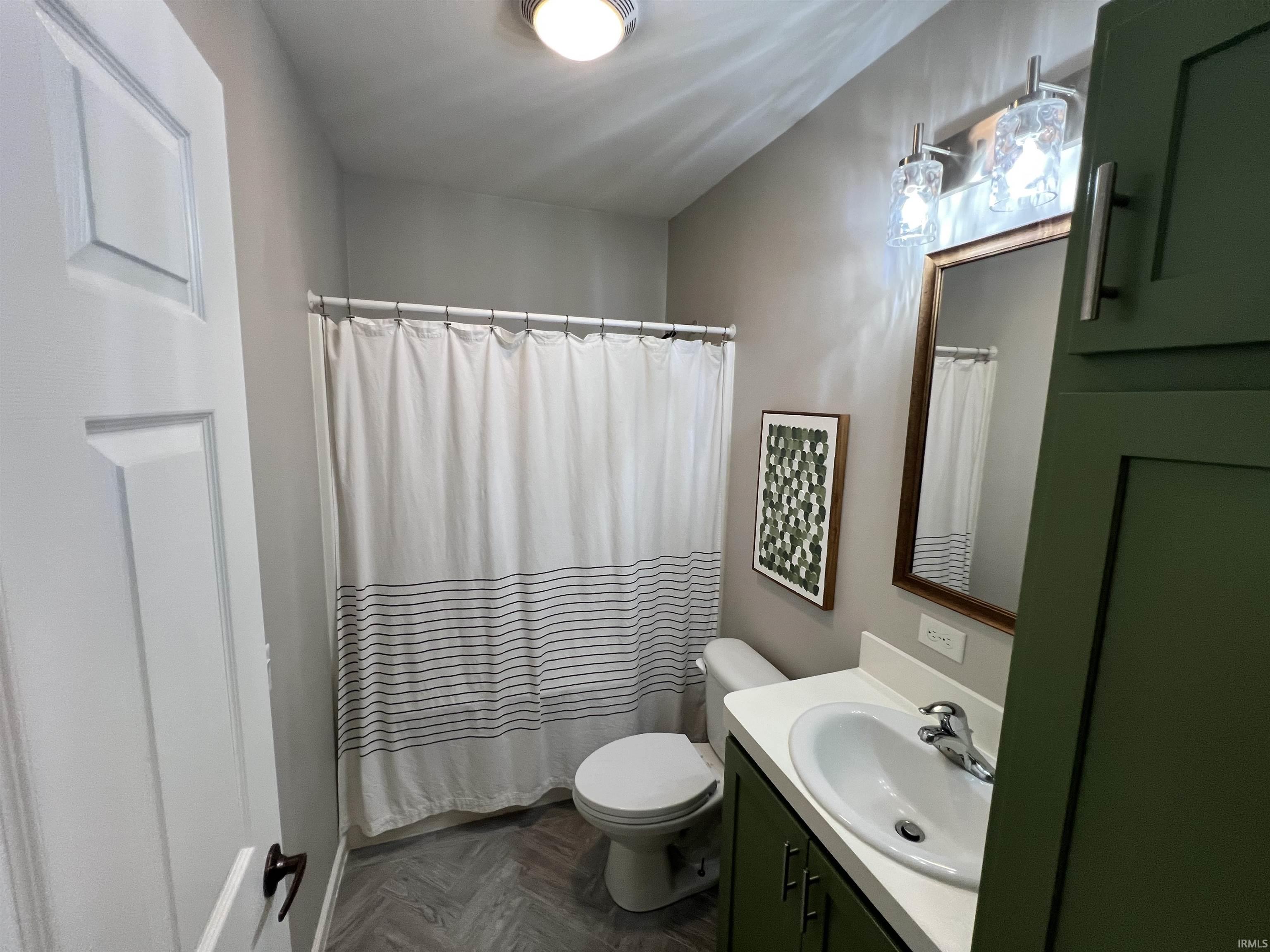 Modern bathroom featuring a single vanity with a white countertop and olive green cabinetry