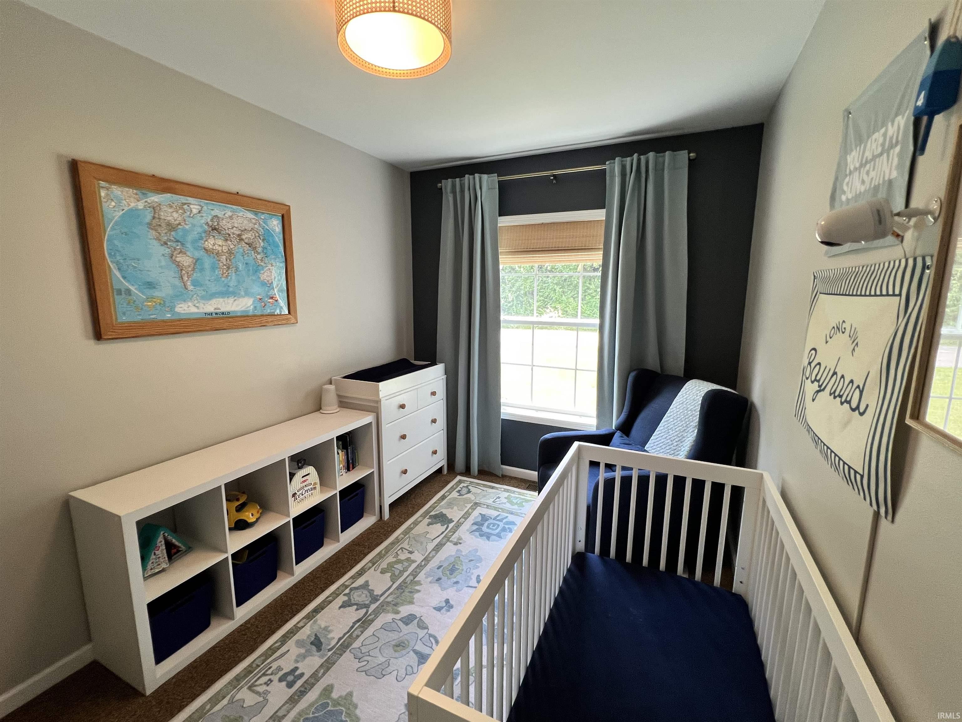 Room featuring two-tone wall paint, a window with blinds and drapes, and wood-finish flooring